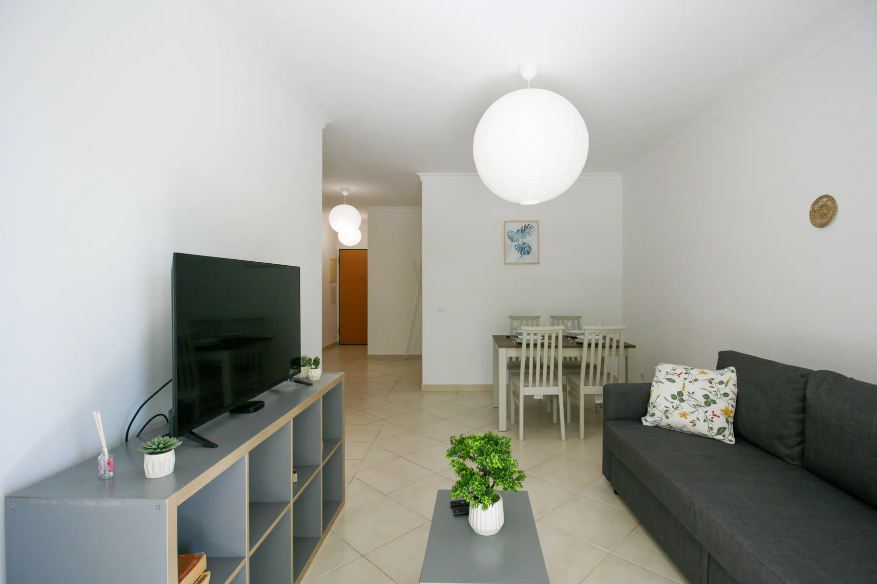 Una luminosa sala de estar y comedor con asientos, un televisor y una mesa.