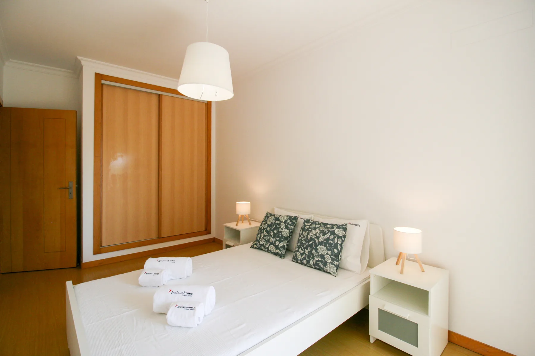 Un dormitorio con una cama, mesitas de noche y persianas correderas de madera.