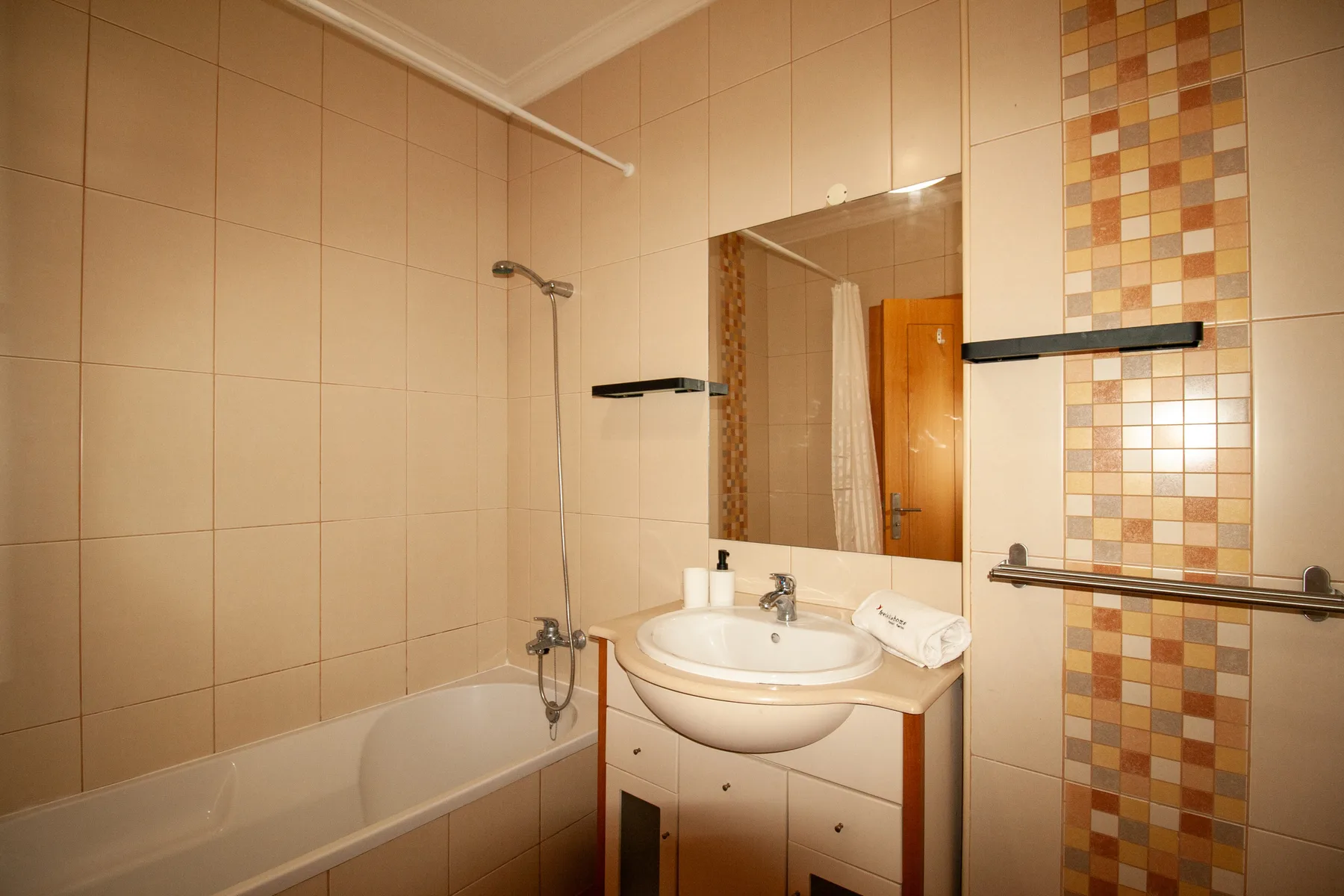Un baño alicatado con bañera, ducha, lavabo y espejo.