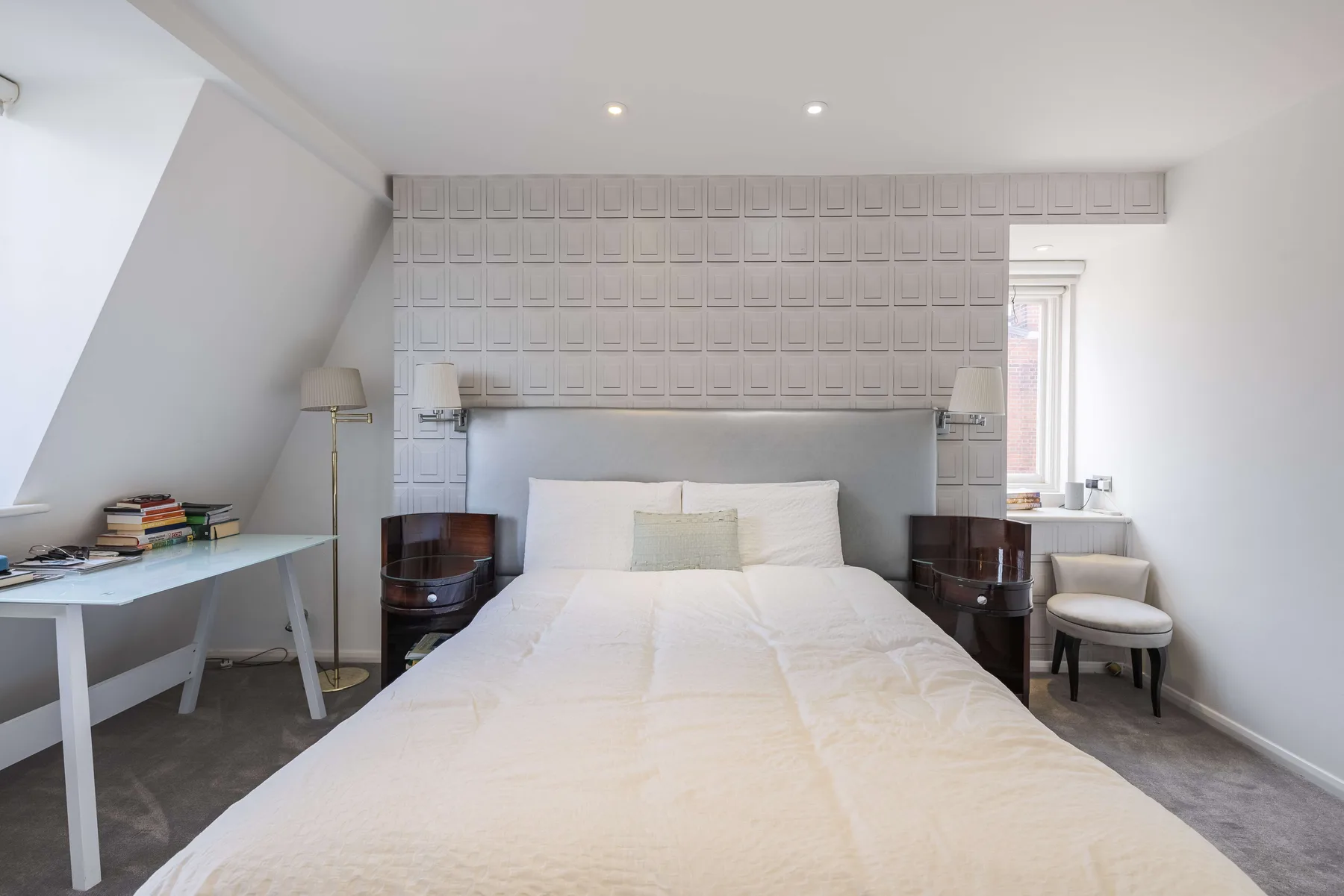 Un dormitorio luminoso con una cama grande, mesitas de noche y una ventana.