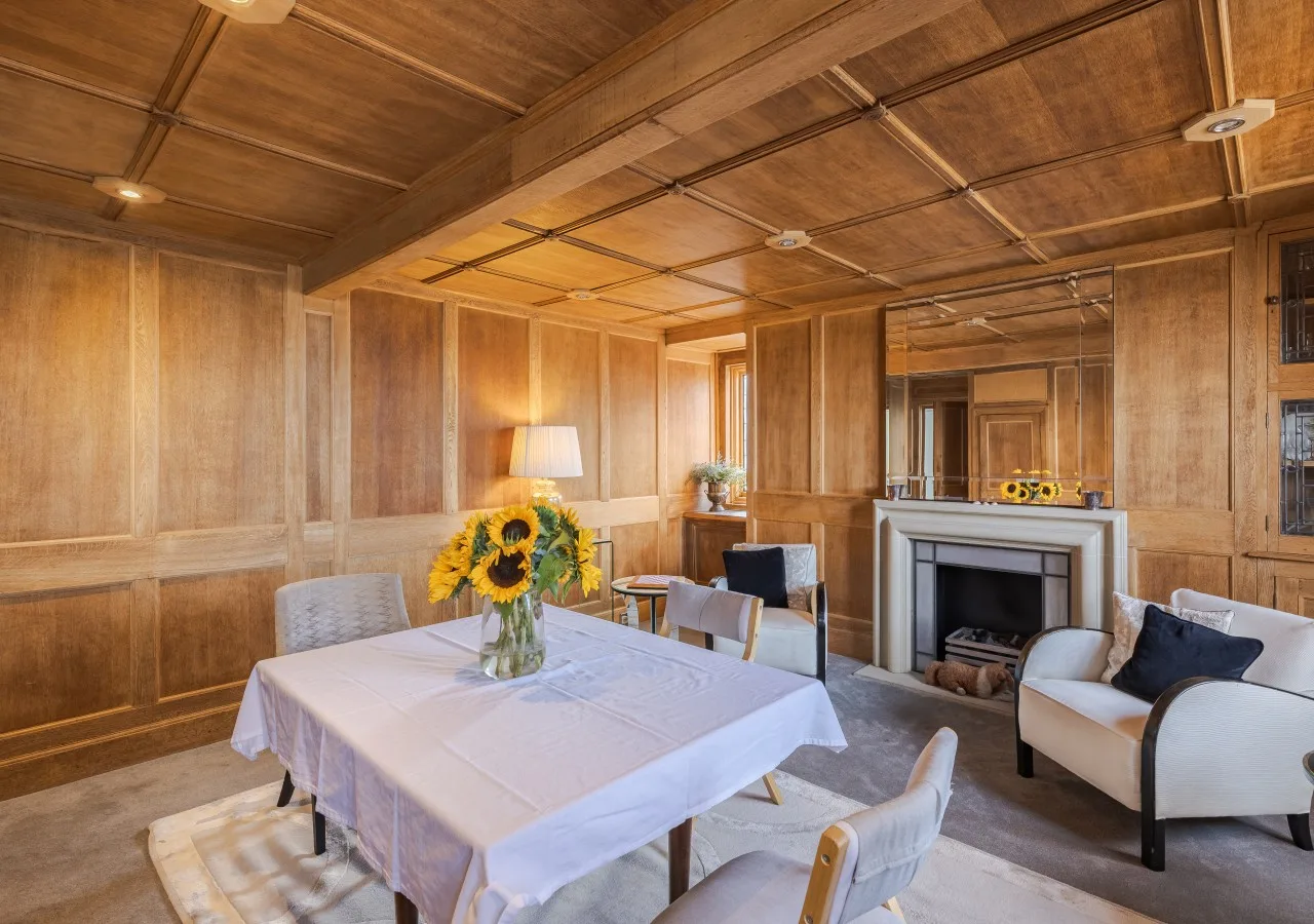 Sala de estar y comedor con paredes revestidas de madera y una mesa con girasoles.