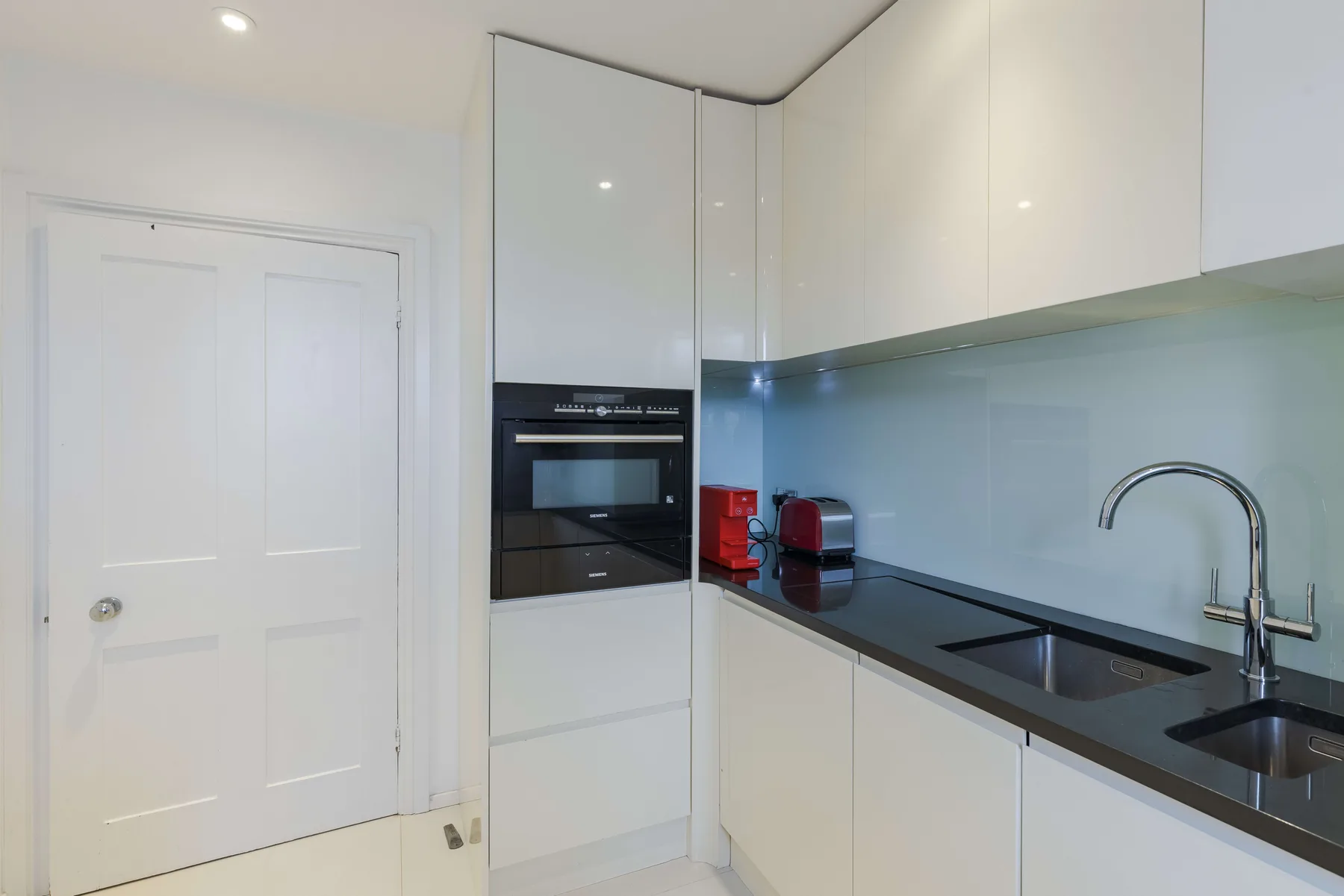 Una cocina moderna y luminosa con gabinetes blancos, una encimera oscura y un fregadero.