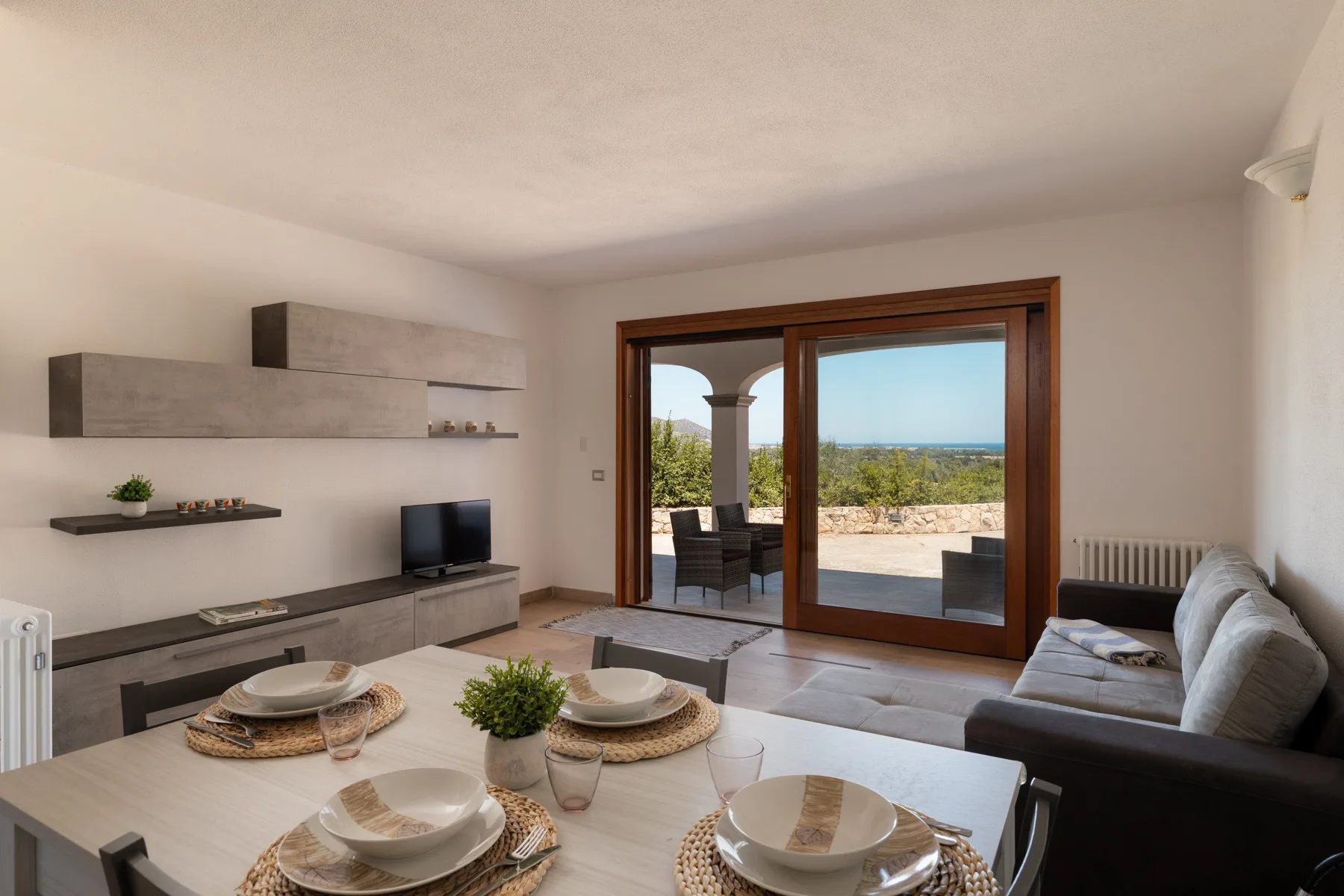 A bright living room with a dining table and sliding glass doors opening to a patio.