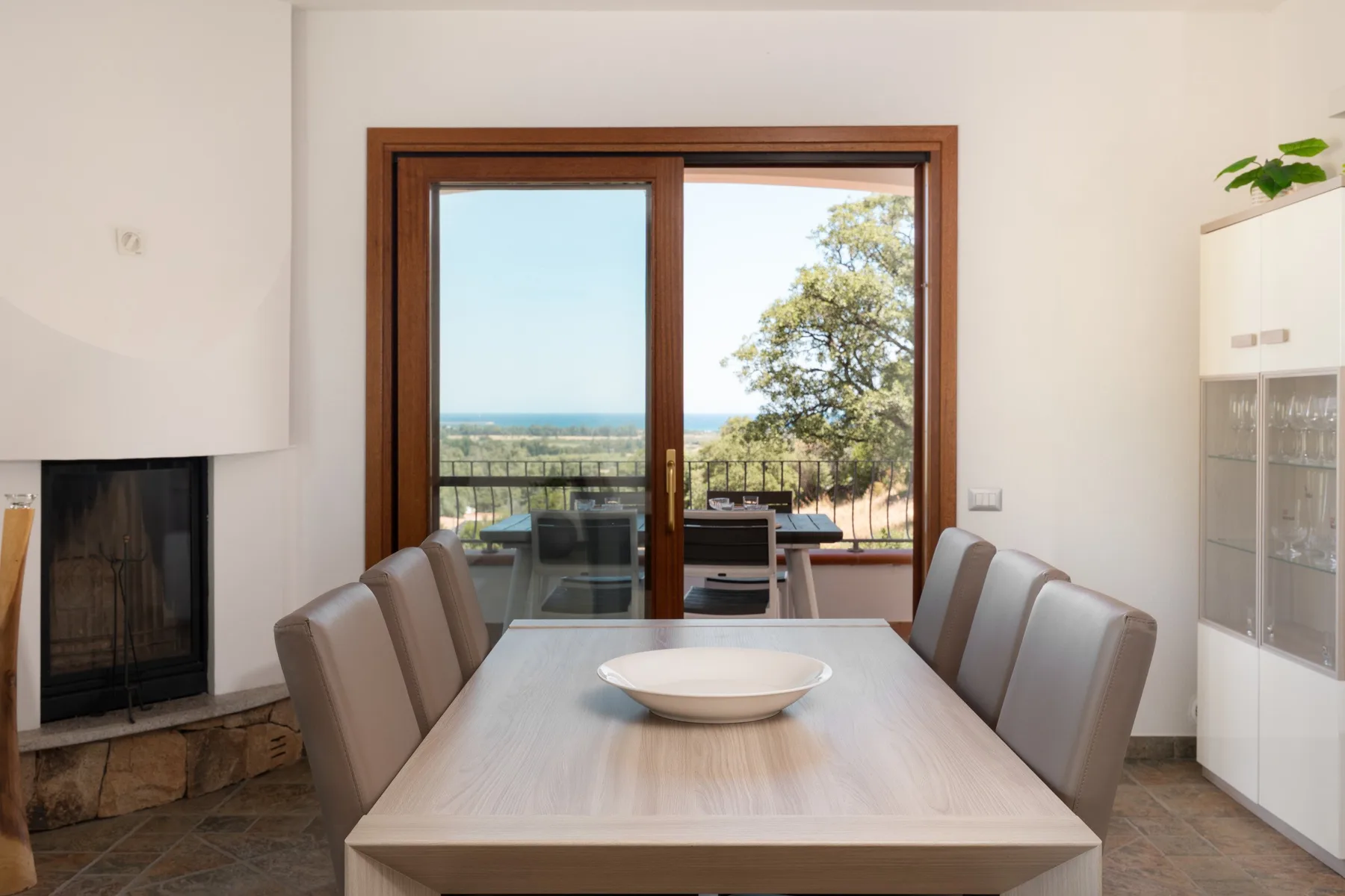 A dining area with a table and seating beside a large glass door.