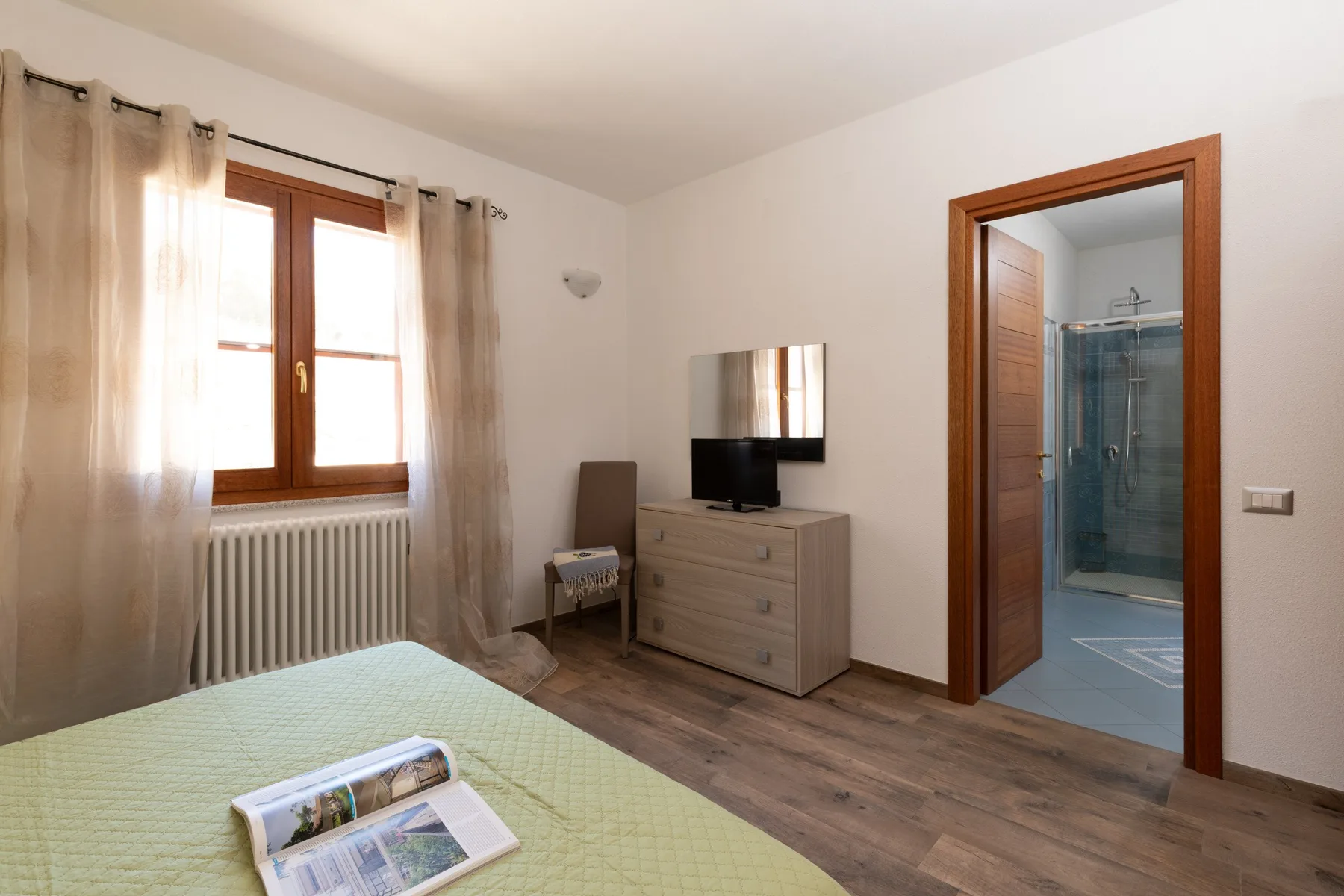 A bedroom with a bed, dresser, and an open doorway to a bathroom.
