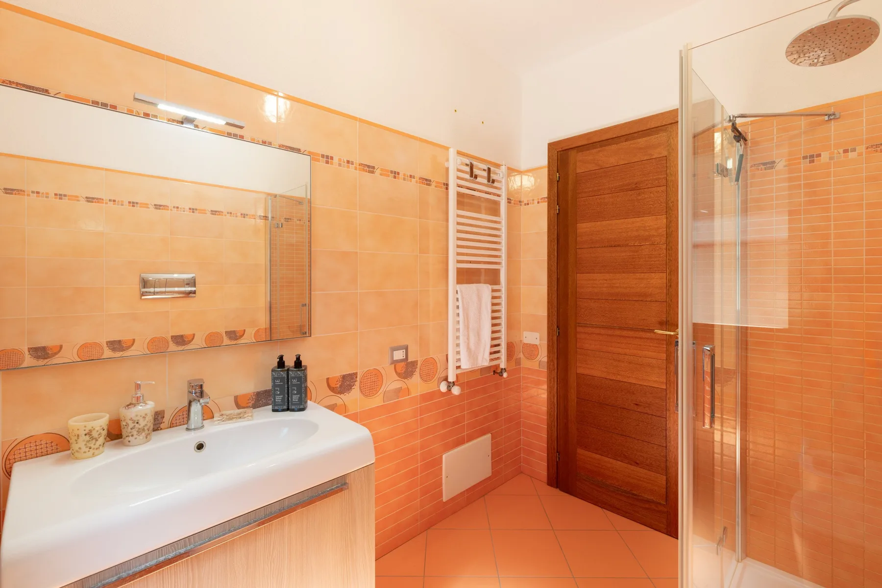 A tiled bathroom with a sink, mirror, and glass shower.