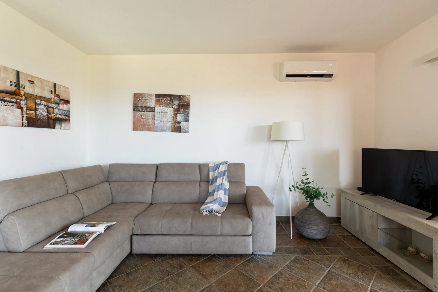 Living room with sectional seating, a floor lamp, and a television.