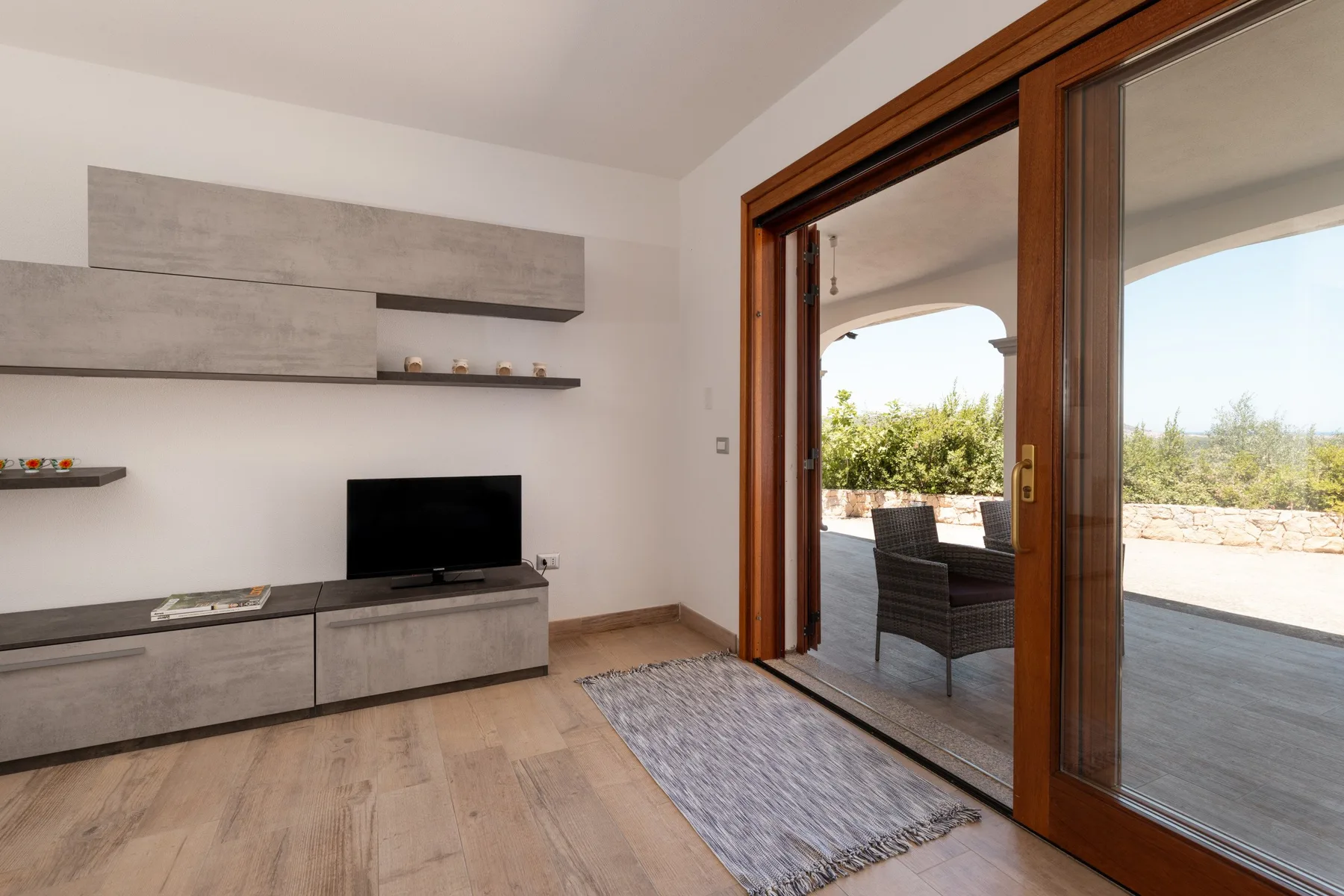 A living room with a television and sliding glass doors opening onto a patio.