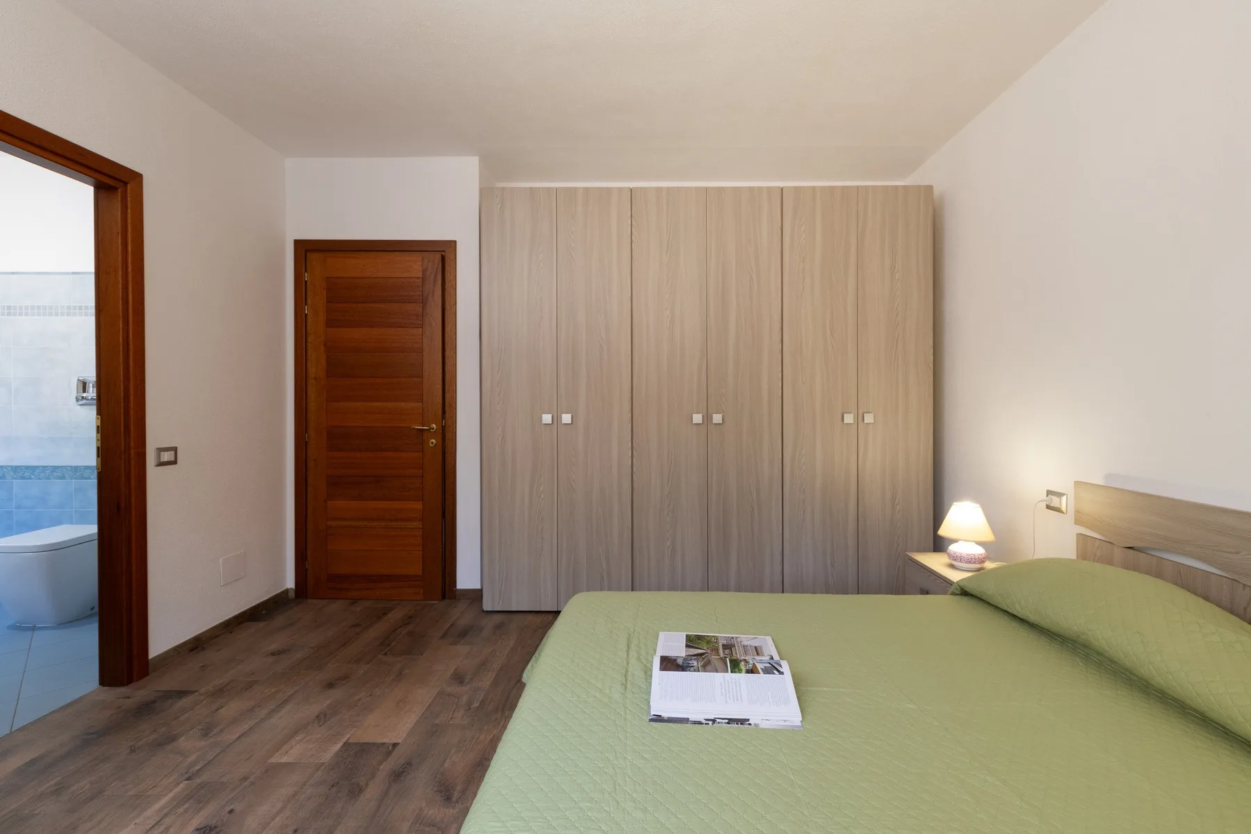 Bedroom with a green bed beside a large wardrobe.