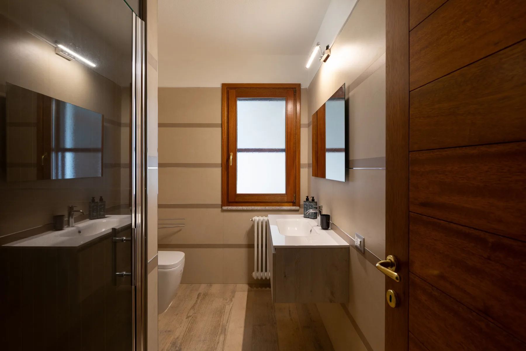 A bathroom with a sink, mirror, and frosted window.