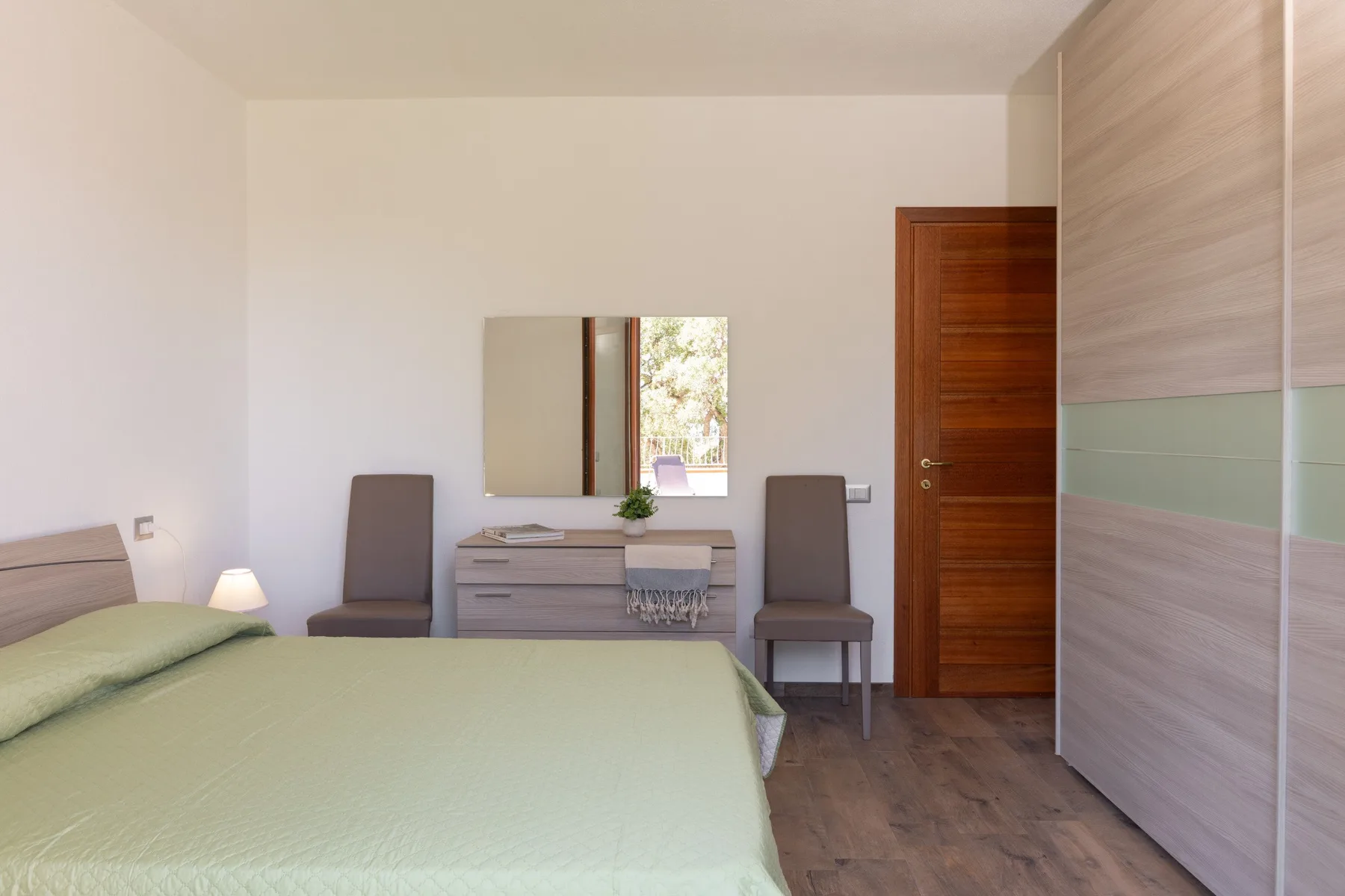 A bedroom with a bed, a dresser and a large wardrobe.