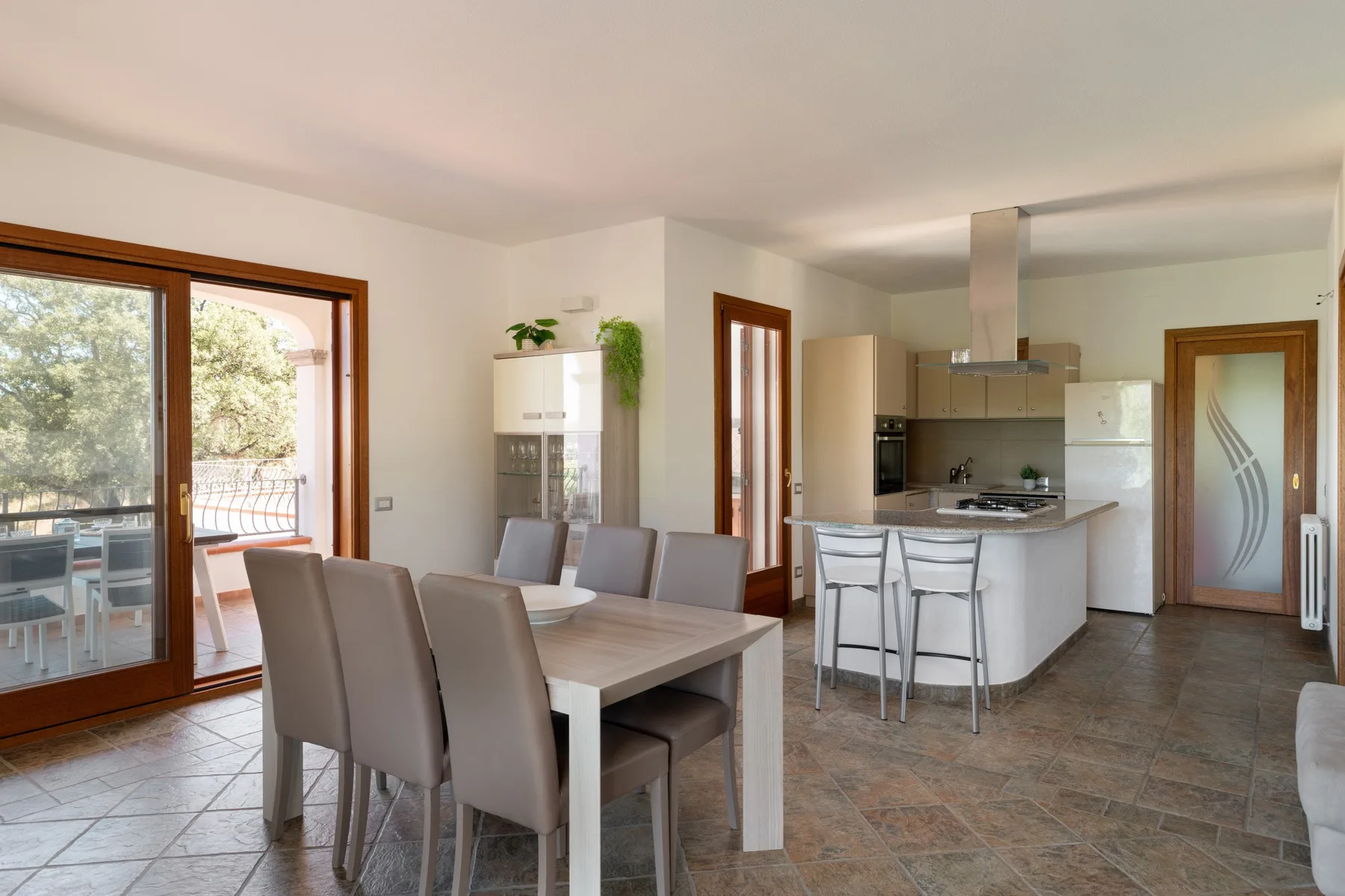 A dining area opens onto a kitchen, with a glass door leading to a patio.