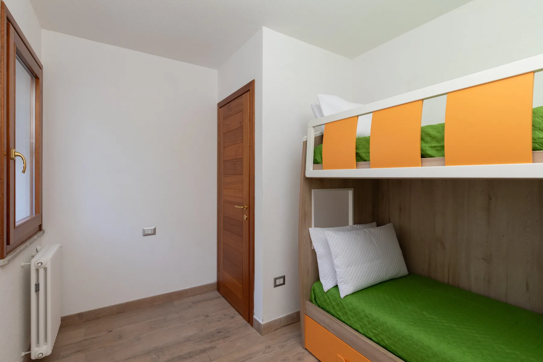 A bedroom with a green lower bunk and orange panels on the upper bunk.