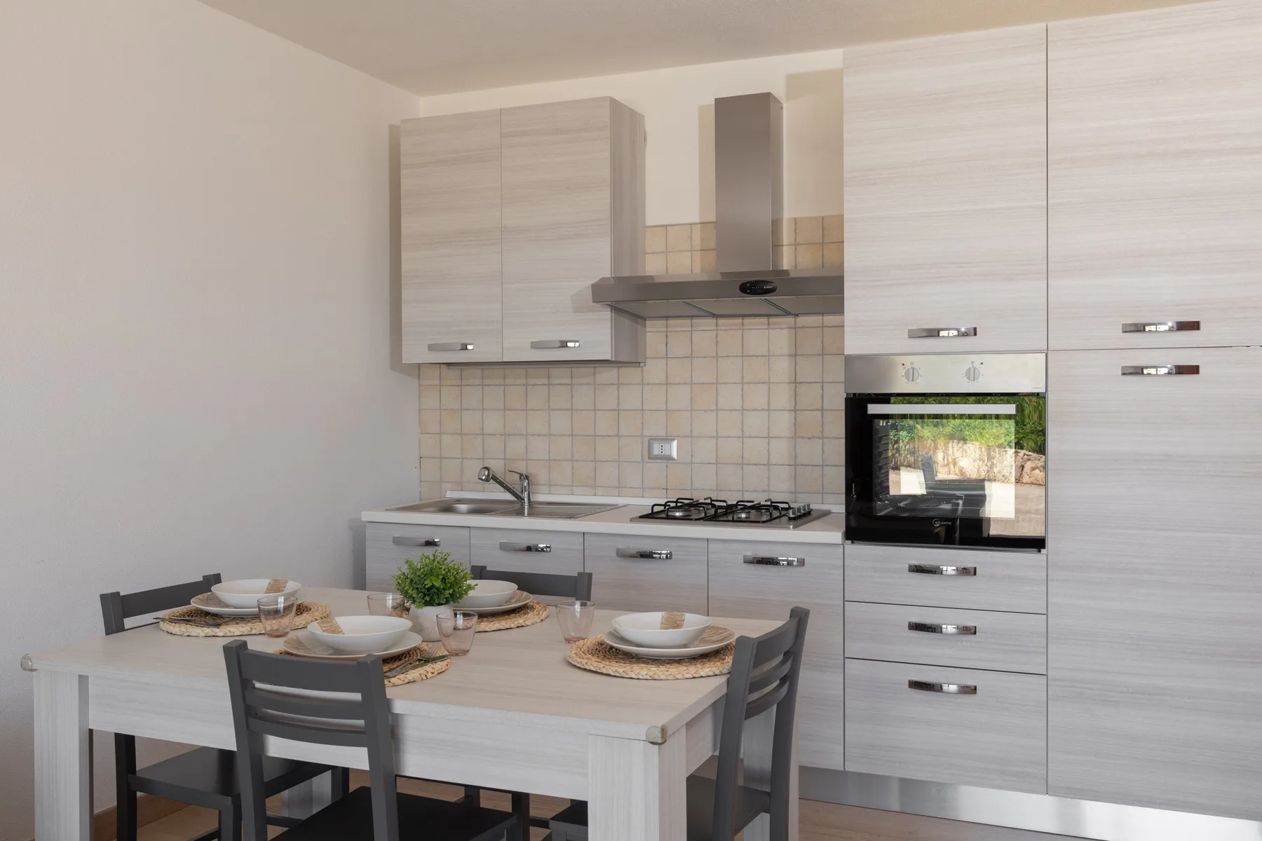 A kitchen and dining area with a table set in front of the cabinets.