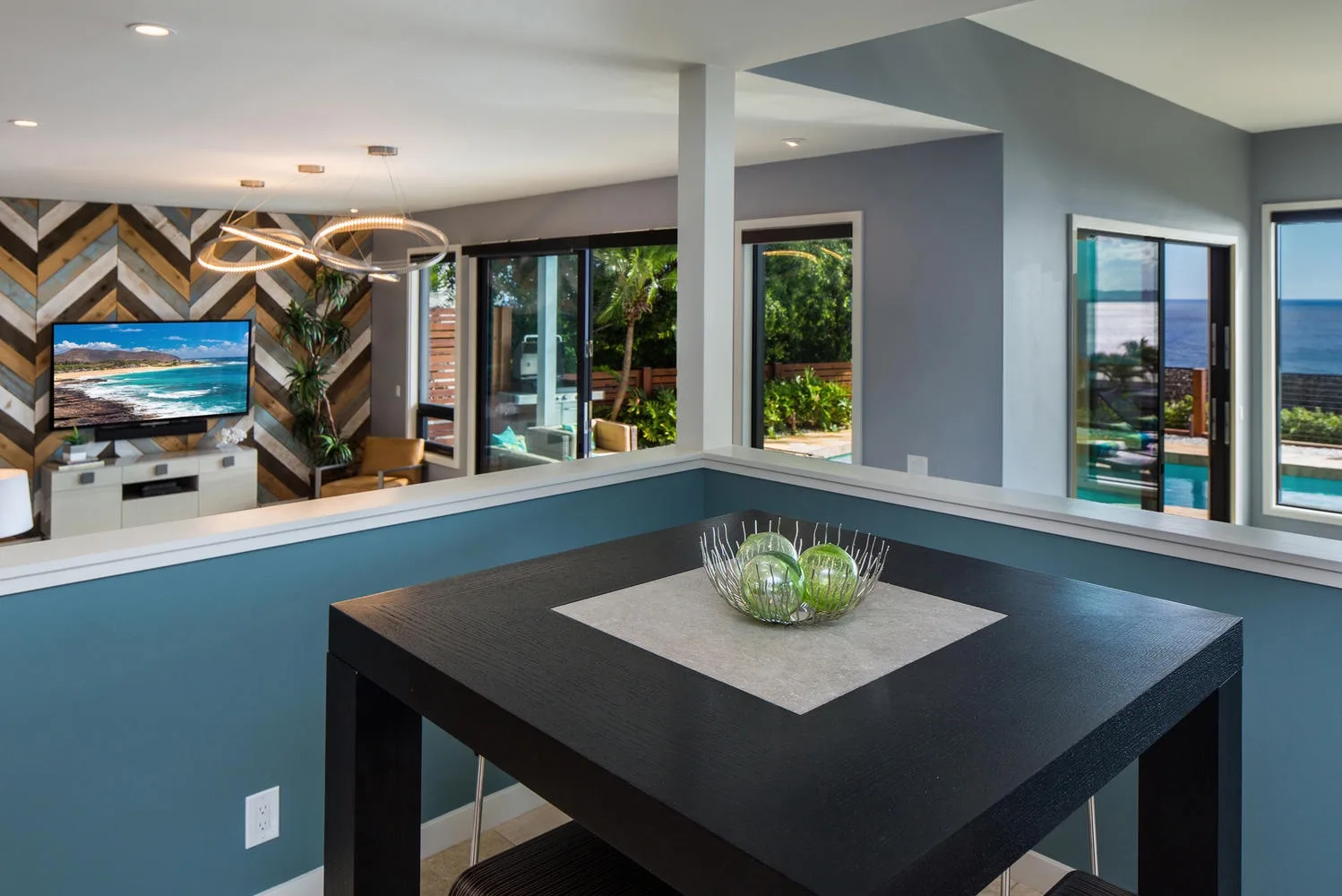 Un comedor moderno con una mesa oscura con vistas a una sala de estar y un jardín.