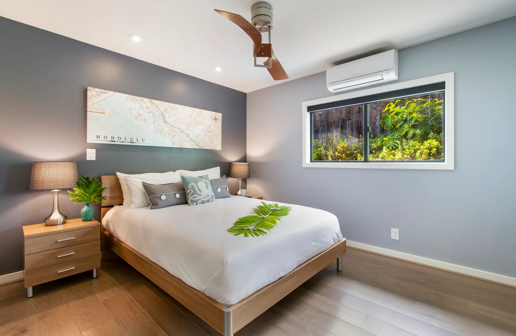 Un dormitorio con una cama bien tendida y una ventana con vista a la vegetación.