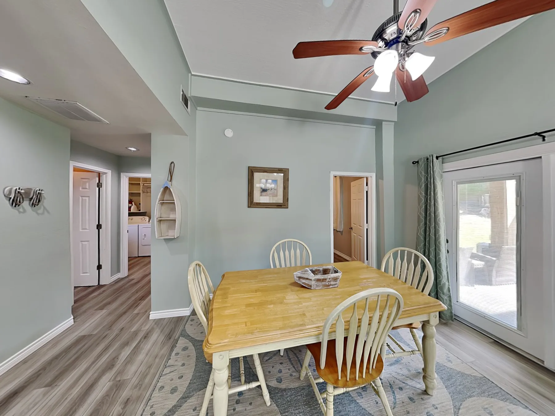 A dining area with a wooden table and chairs beside a glass patio door.