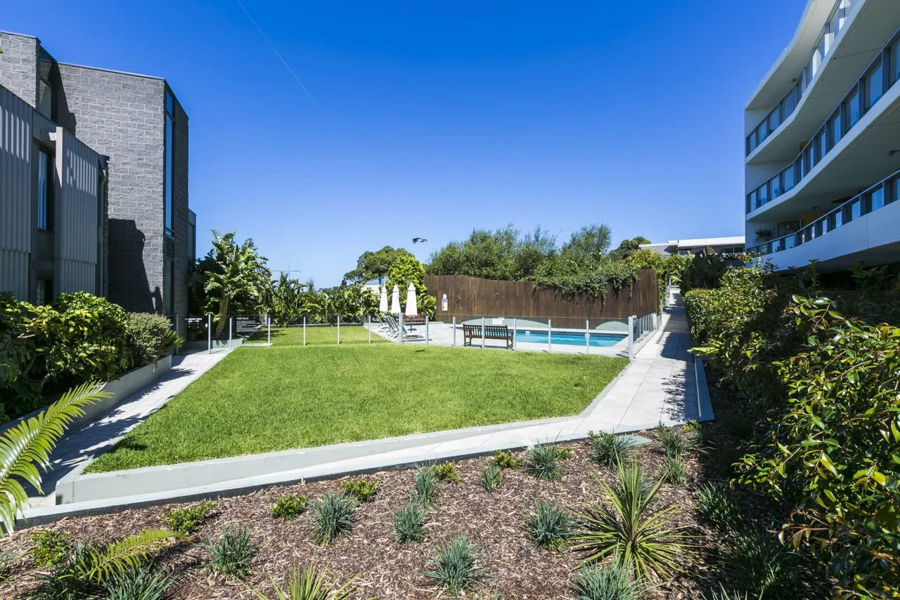 An outdoor courtyard with a lawn, swimming pool, and surrounding buildings.