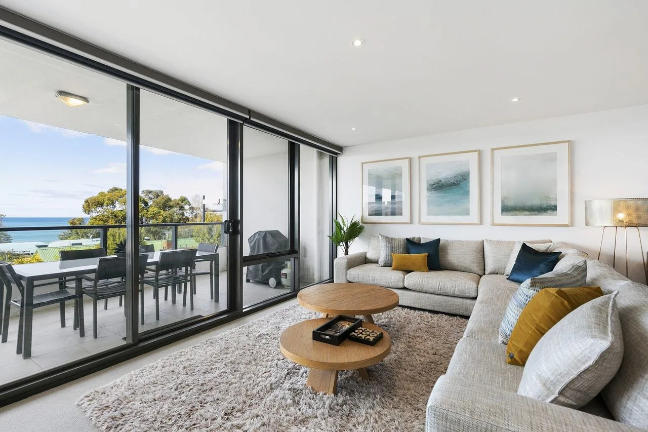 Living room with seating and large glass doors opening onto a balcony.