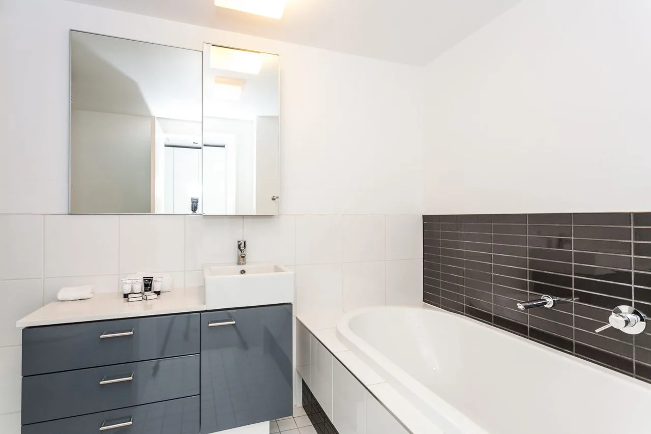 A bathroom with a bathtub, vanity, and large wall mirror.