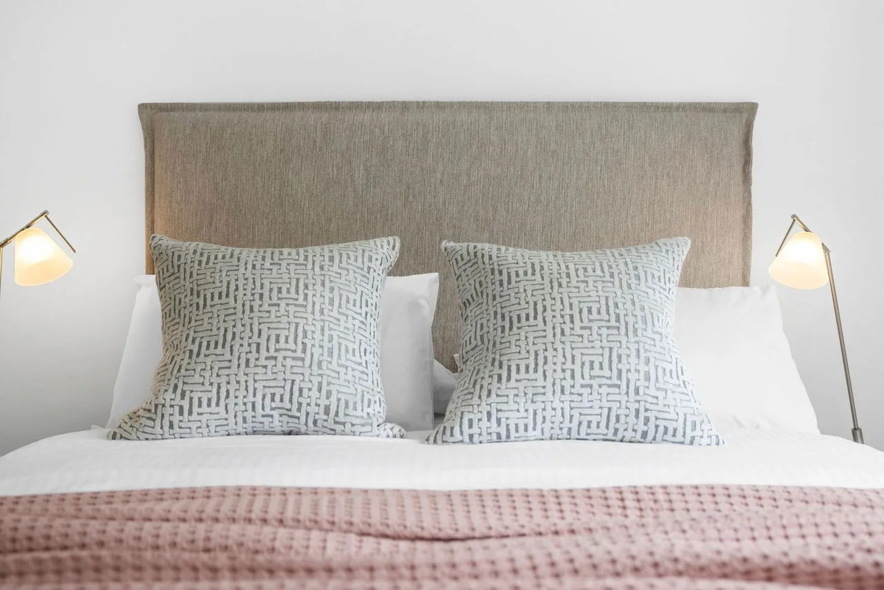 A bedroom with a bed, patterned pillows, and bedside lamps.
