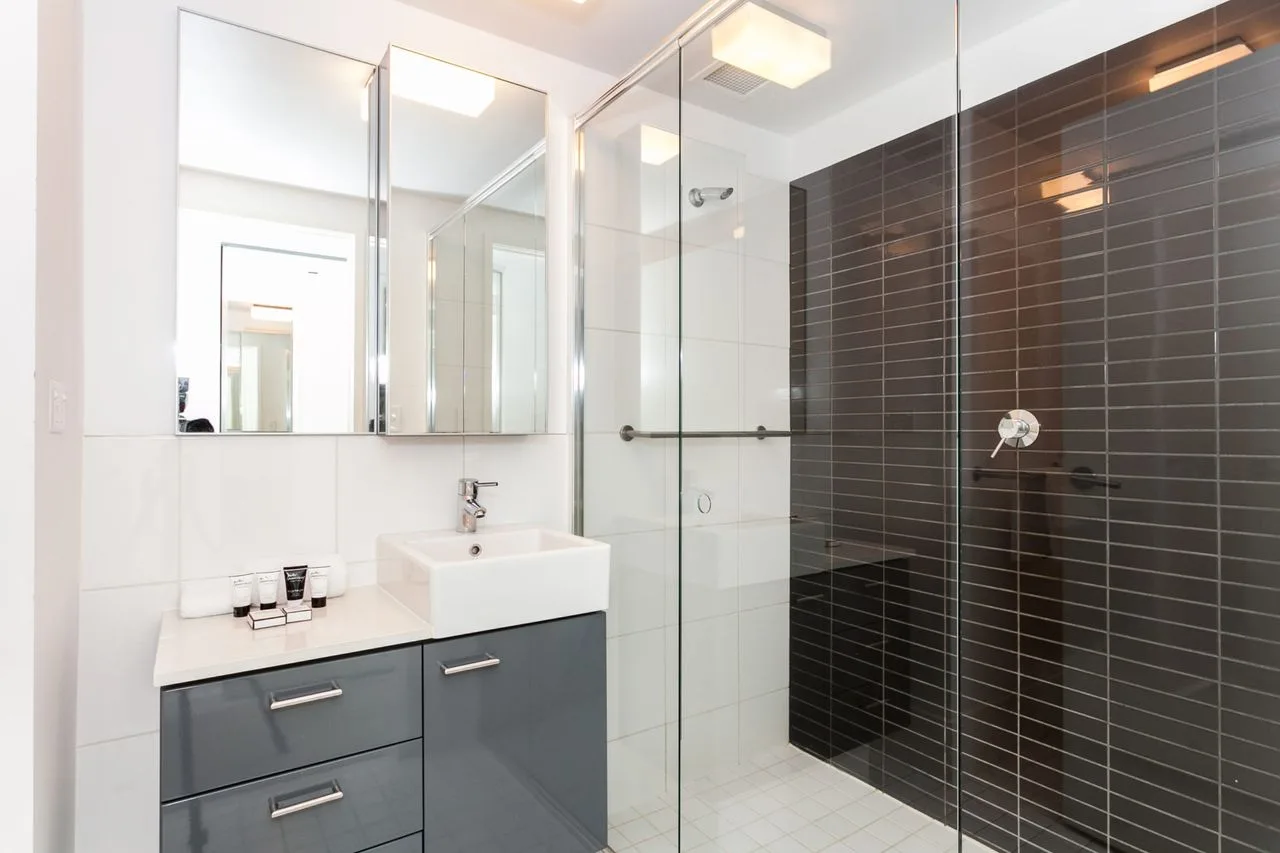 A bright bathroom with a sink vanity and glass shower.