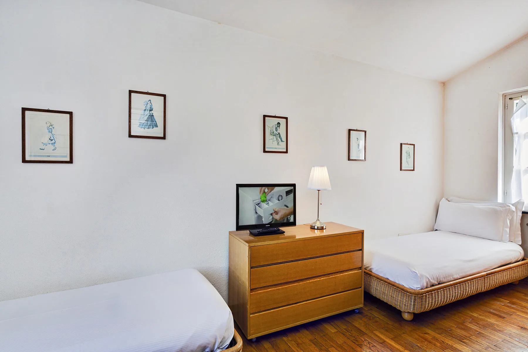 Un dormitorio con dos camas, una cómoda de madera y cuadros en la pared.