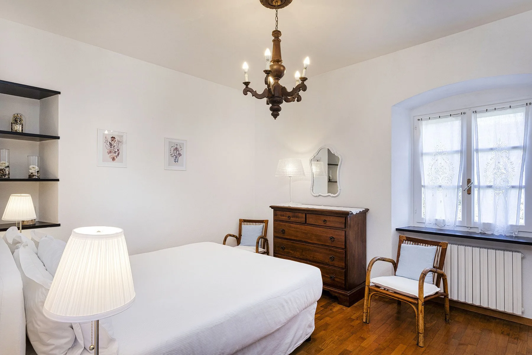 Un dormitorio luminoso con una cama, una cómoda de madera y una ventana.