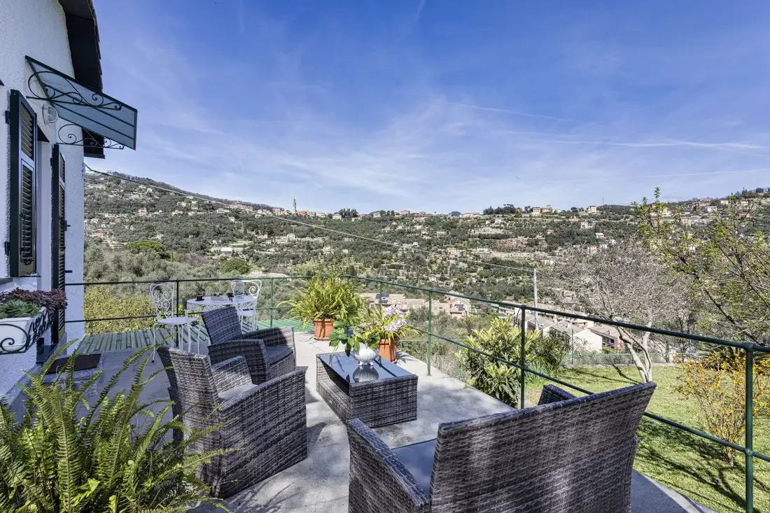 Una terraza amueblada ofrece vistas a una ladera verde bajo un cielo despejado.