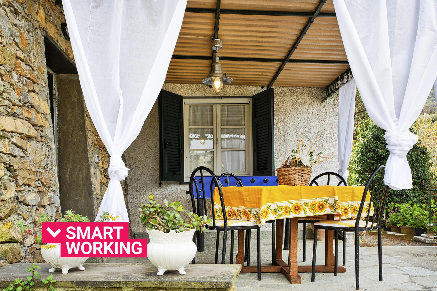 Un comedor exterior cubierto con una mesa, sillas y cortinas blancas.