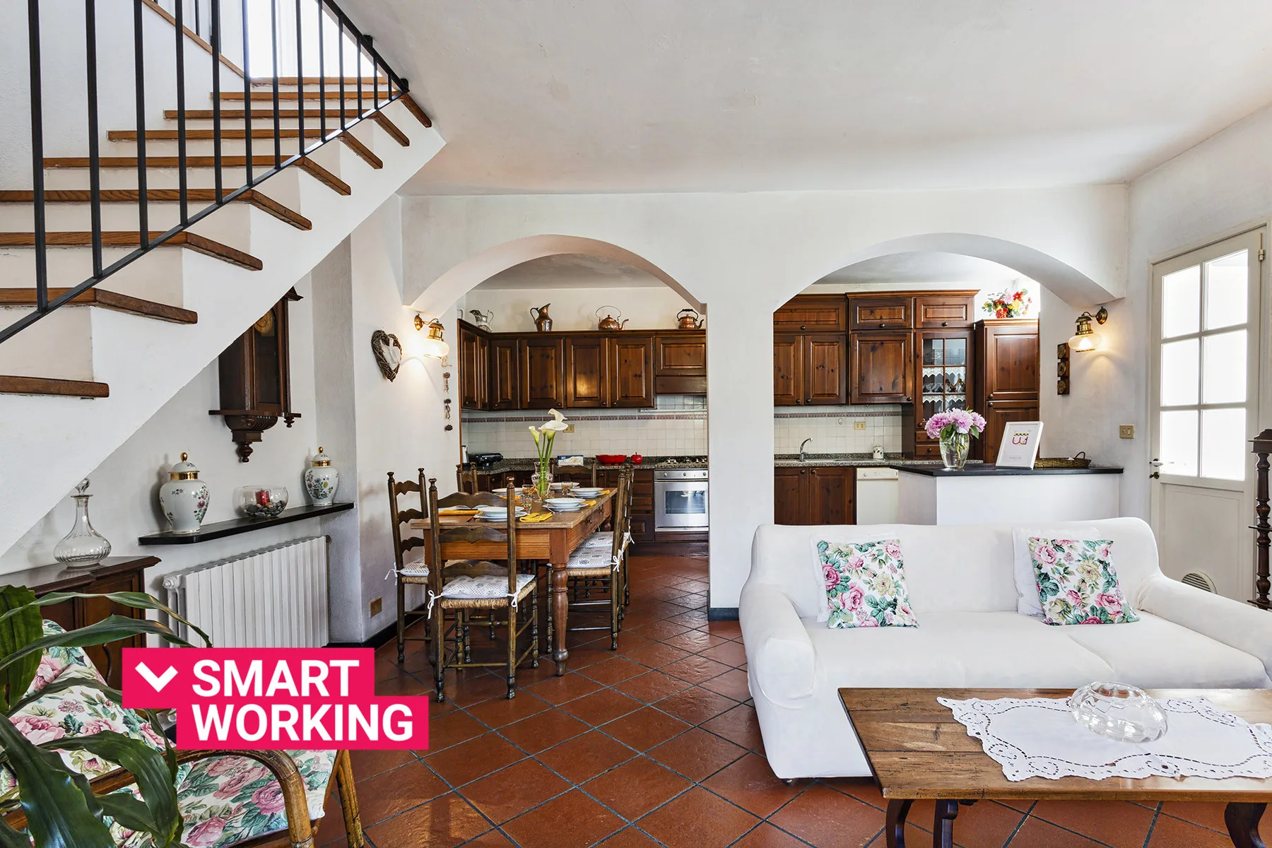 Una sala de estar y una cocina comparten un espacio abierto bajo una escalera.