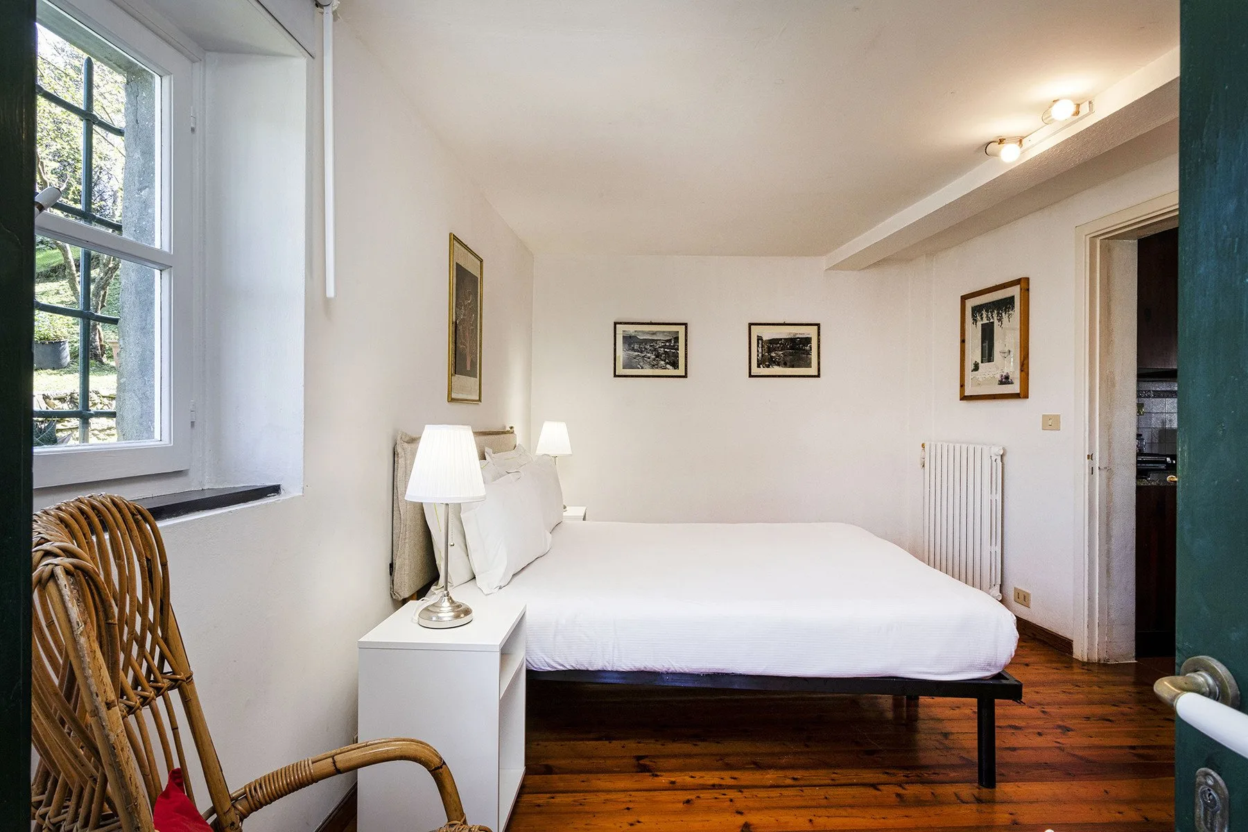 Un dormitorio luminoso con una cama bien tendida y una ventana grande.