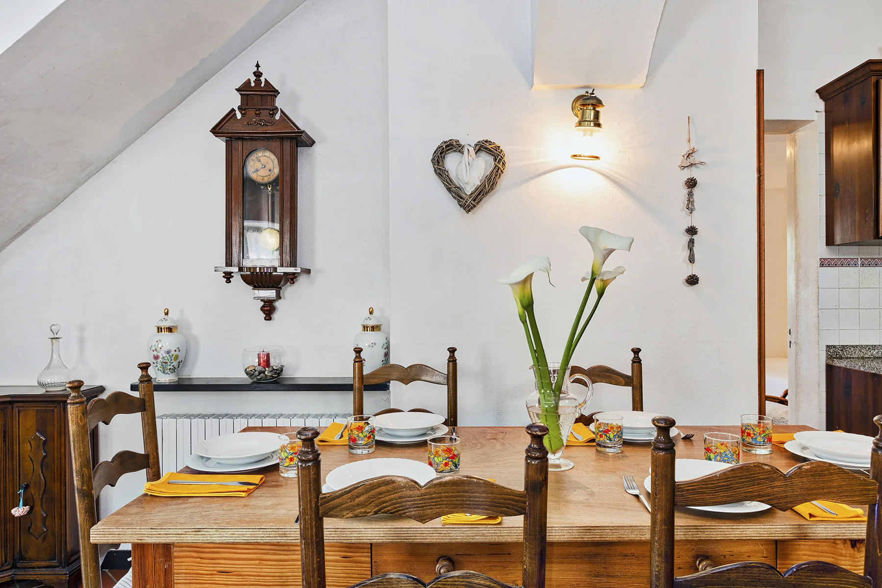 Comedor con mesa de madera, sillas y flores.