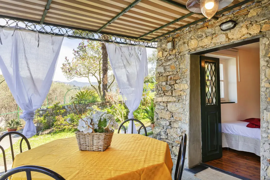 Un comedor exterior cubierto con un mantel amarillo y una pared de piedra.