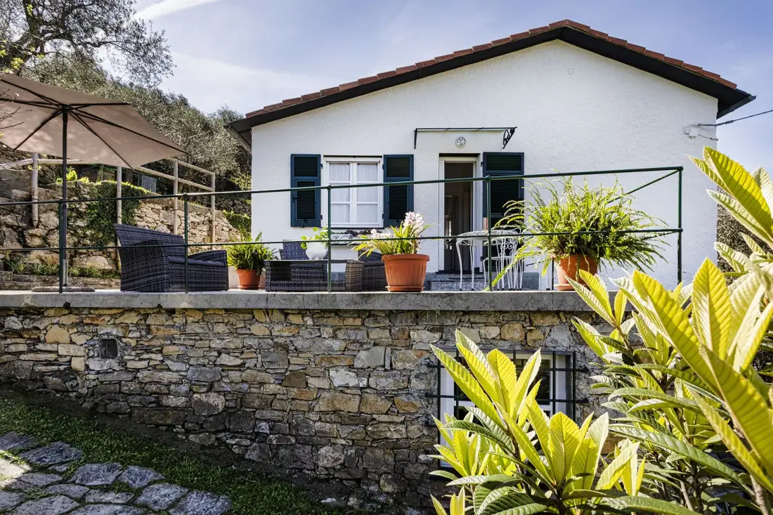 Una casa blanca con patio, asientos al aire libre y plantas en macetas.