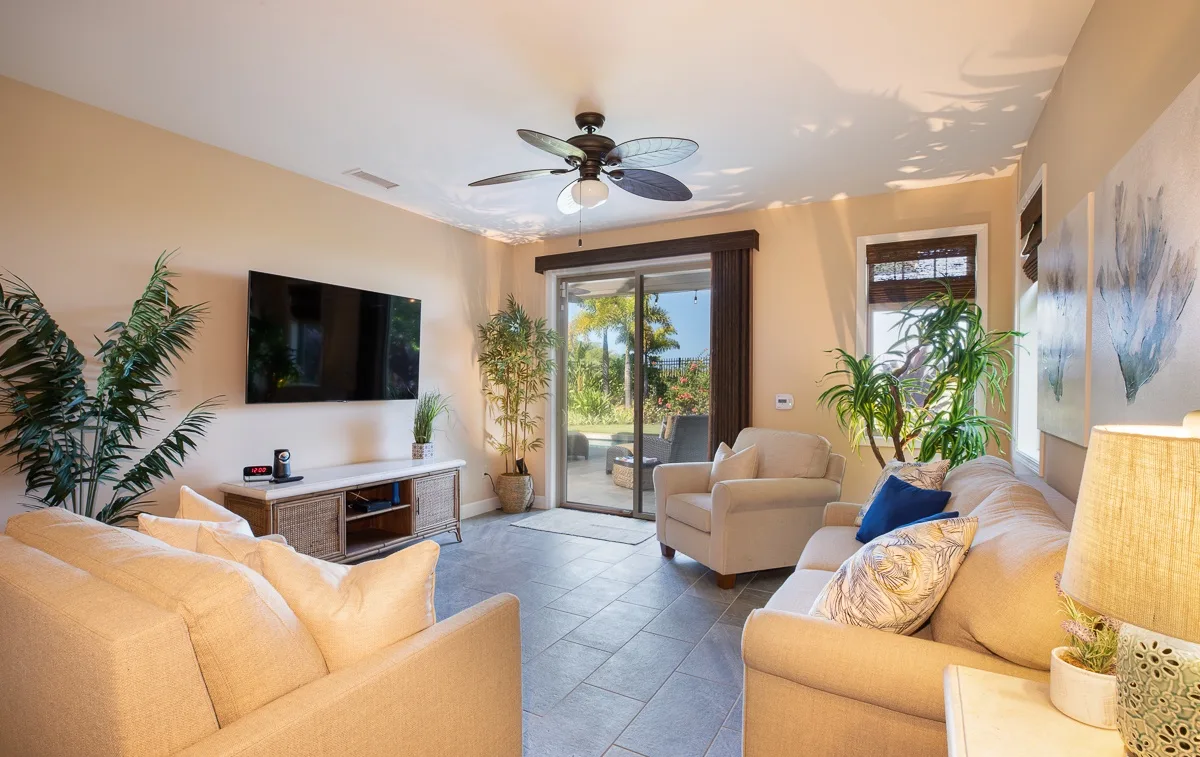 Una sala luminosa con asientos, un televisor y puertas de vidrio que dan a un patio.