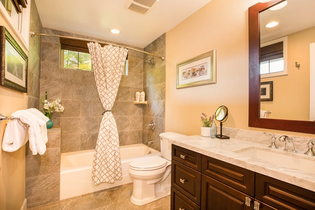 Un baño con bañera, cortina de ducha, inodoro y lavabo con mueble.
