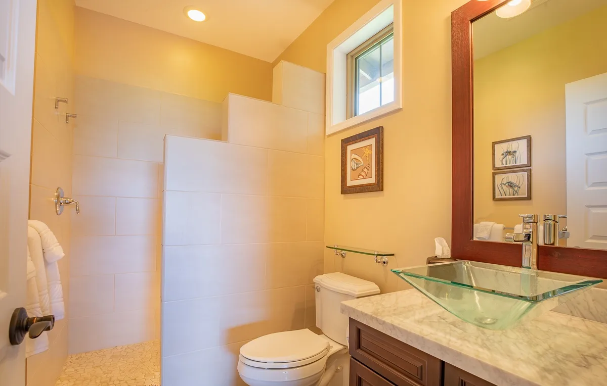 Un baño con un lavabo de vidrio y una ducha.