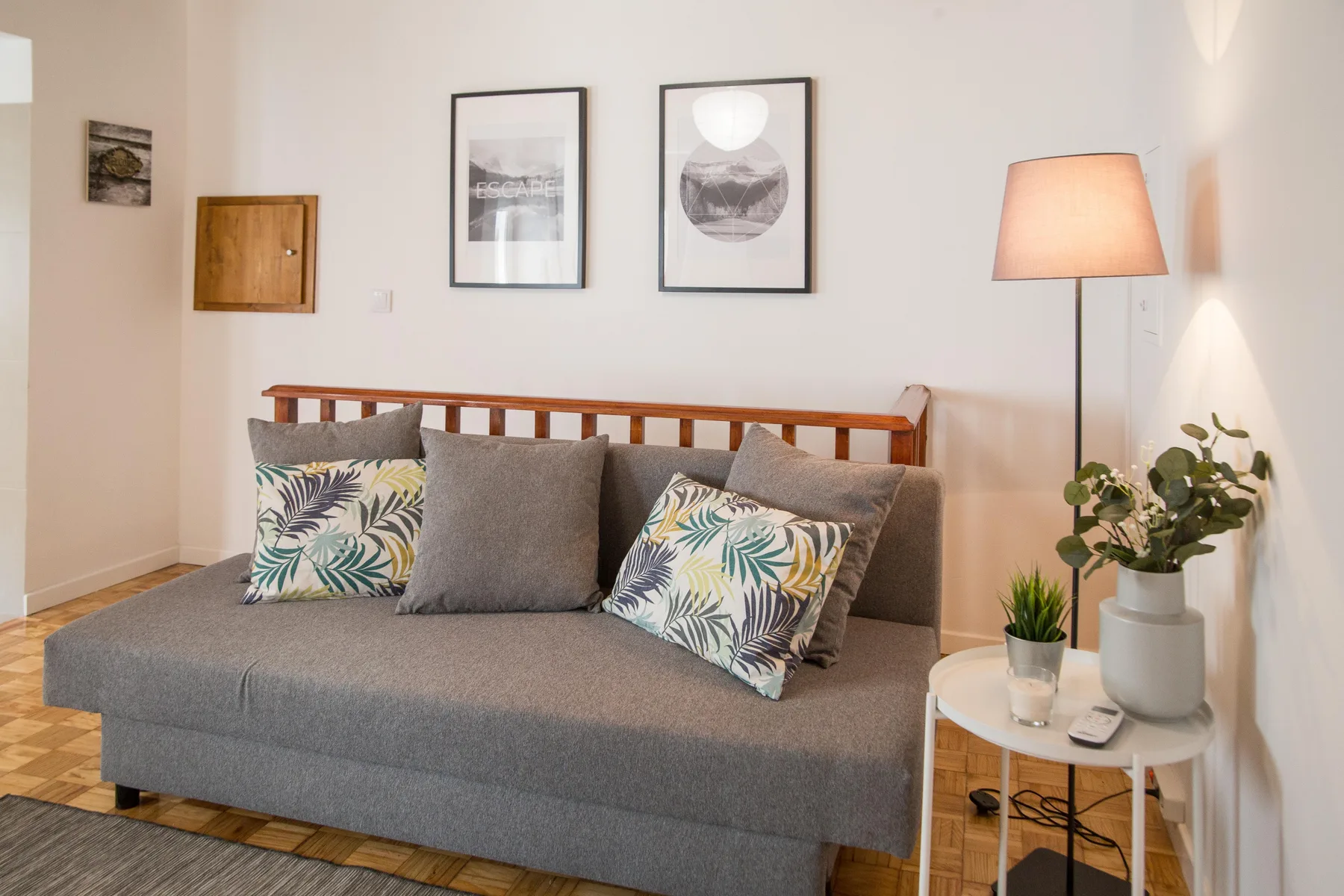 A living room with gray seating, patterned cushions, and a floor lamp.