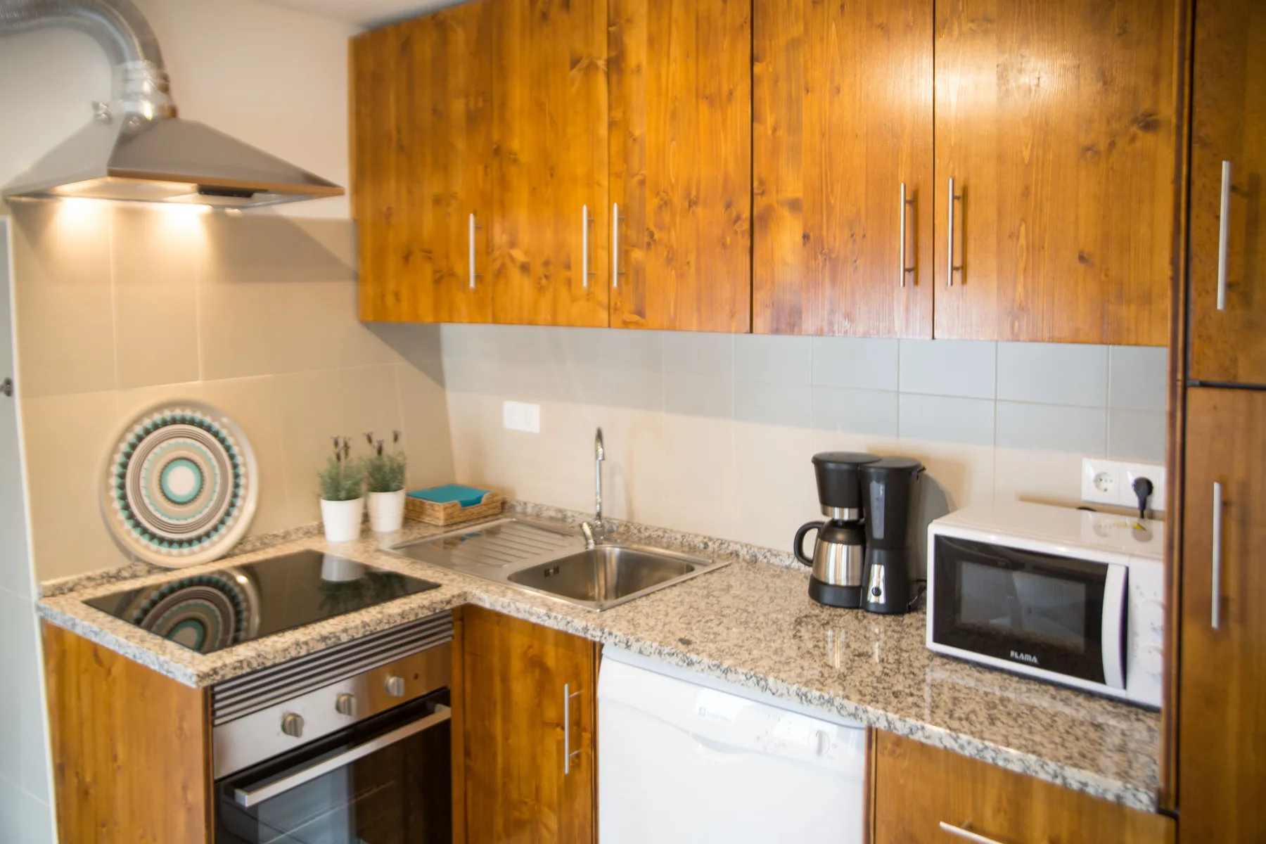 A compact kitchen with wooden cabinets, a countertop, and small appliances.