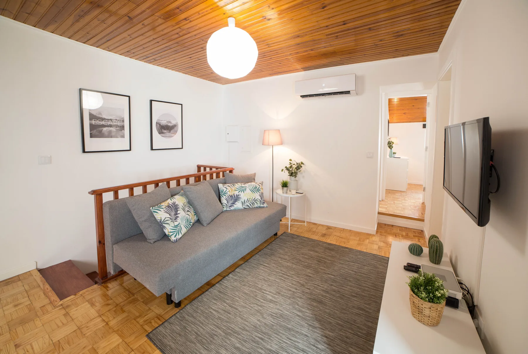 Living room with gray seating, framed wall art, and a wood-paneled ceiling.