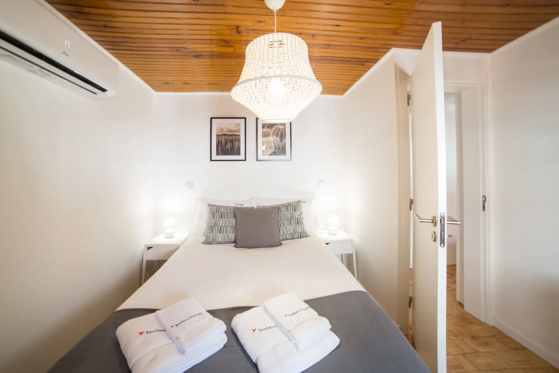 A bedroom with a neatly made bed and a wooden ceiling.