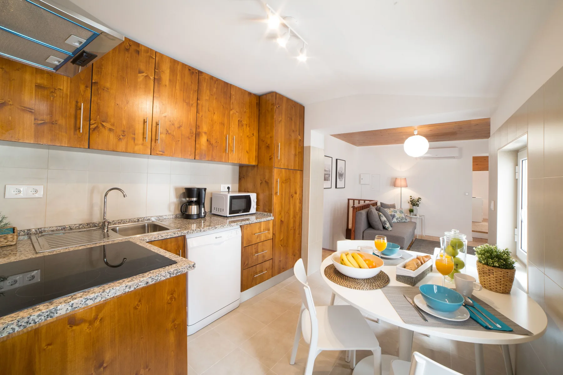 Cocina y comedor de concepto abierto, con gabinetes de madera y una mesa puesta.