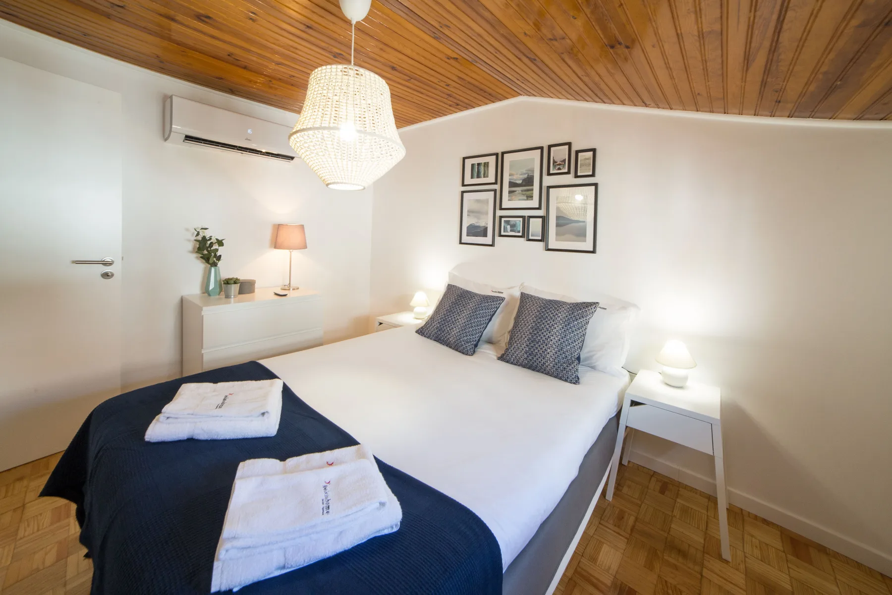 A bedroom with a double bed, bedside tables, and framed pictures on the wall.