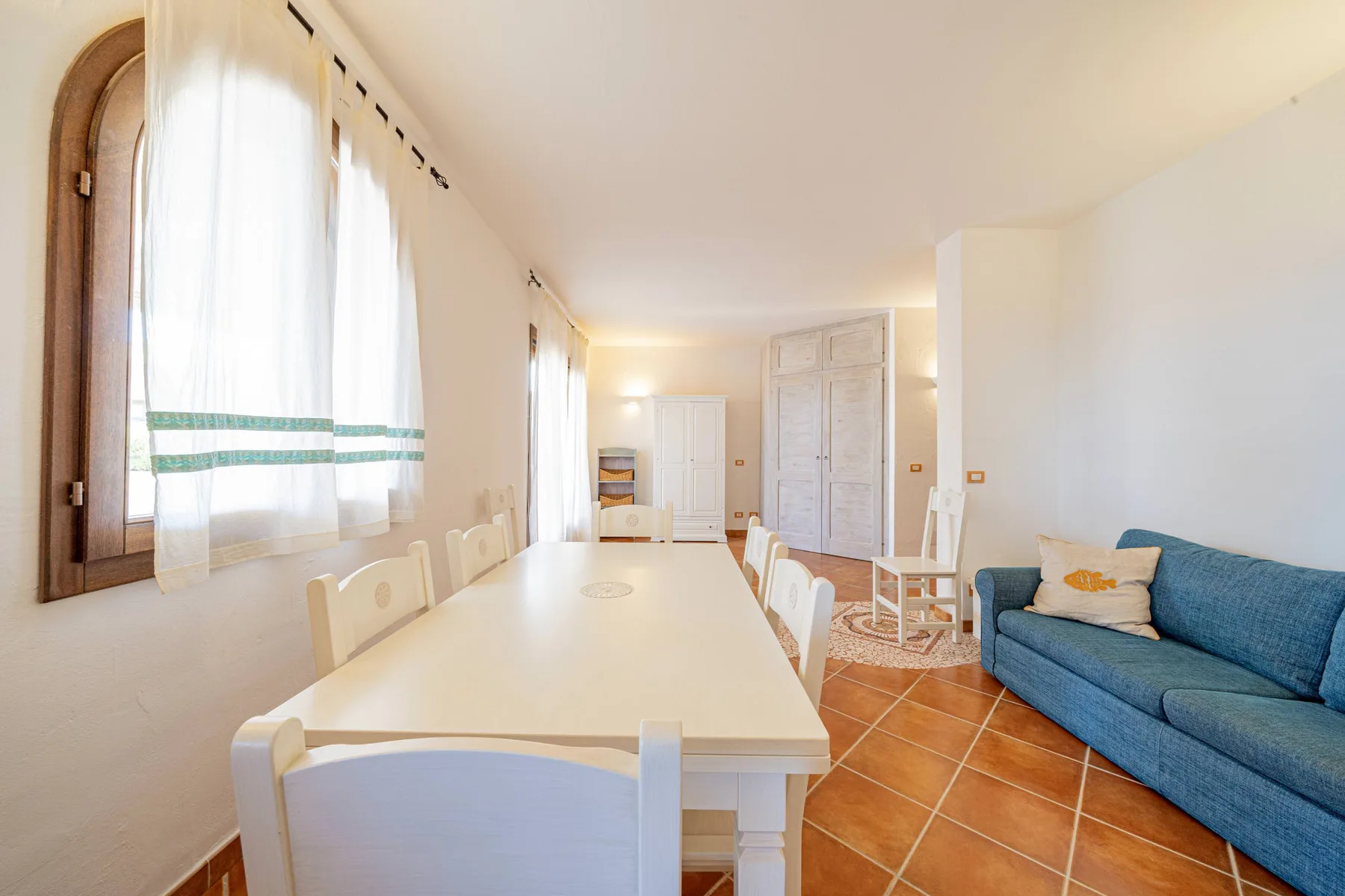Comedor con una mesa larga junto a un sofá azul.