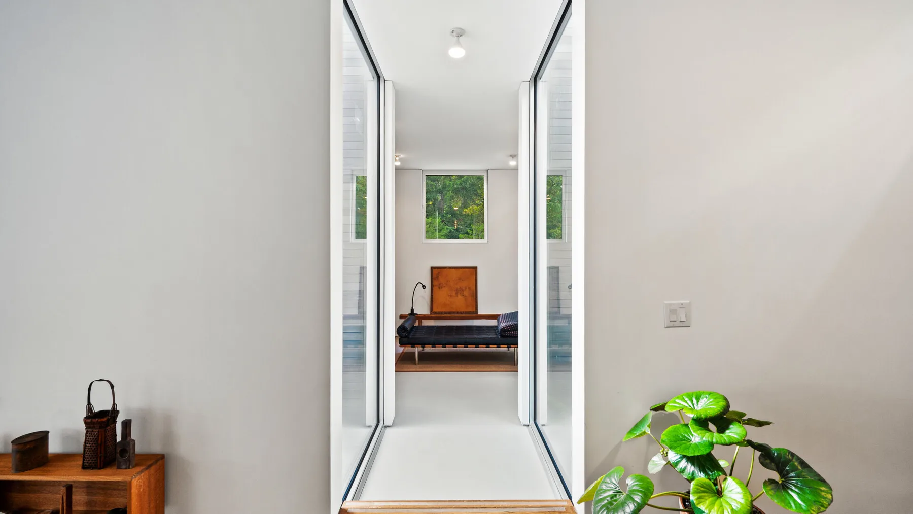 A bright hallway with glass doors opens onto a room with a framed picture.