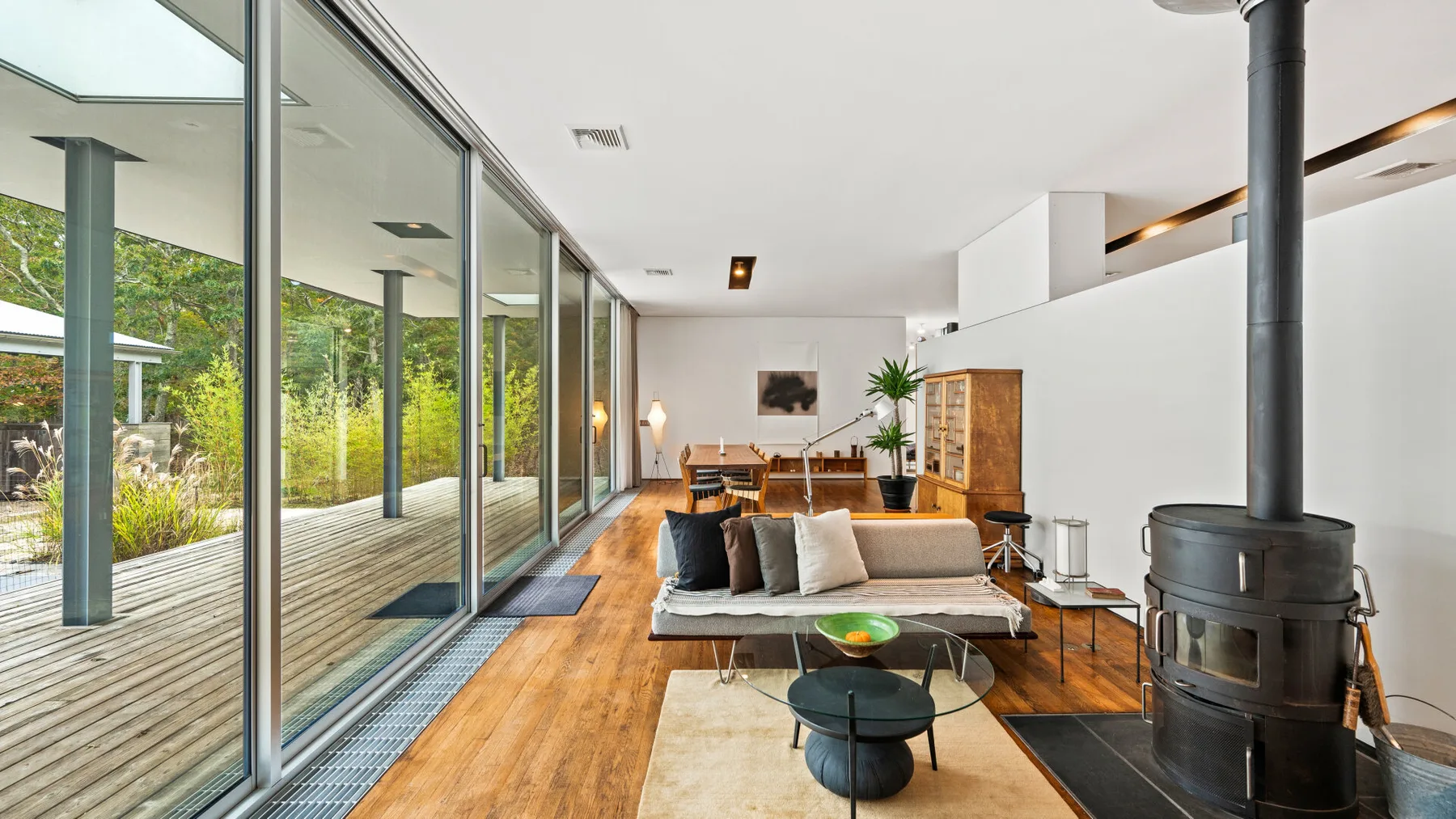 A bright living room with a seating area beside floor-to-ceiling windows.
