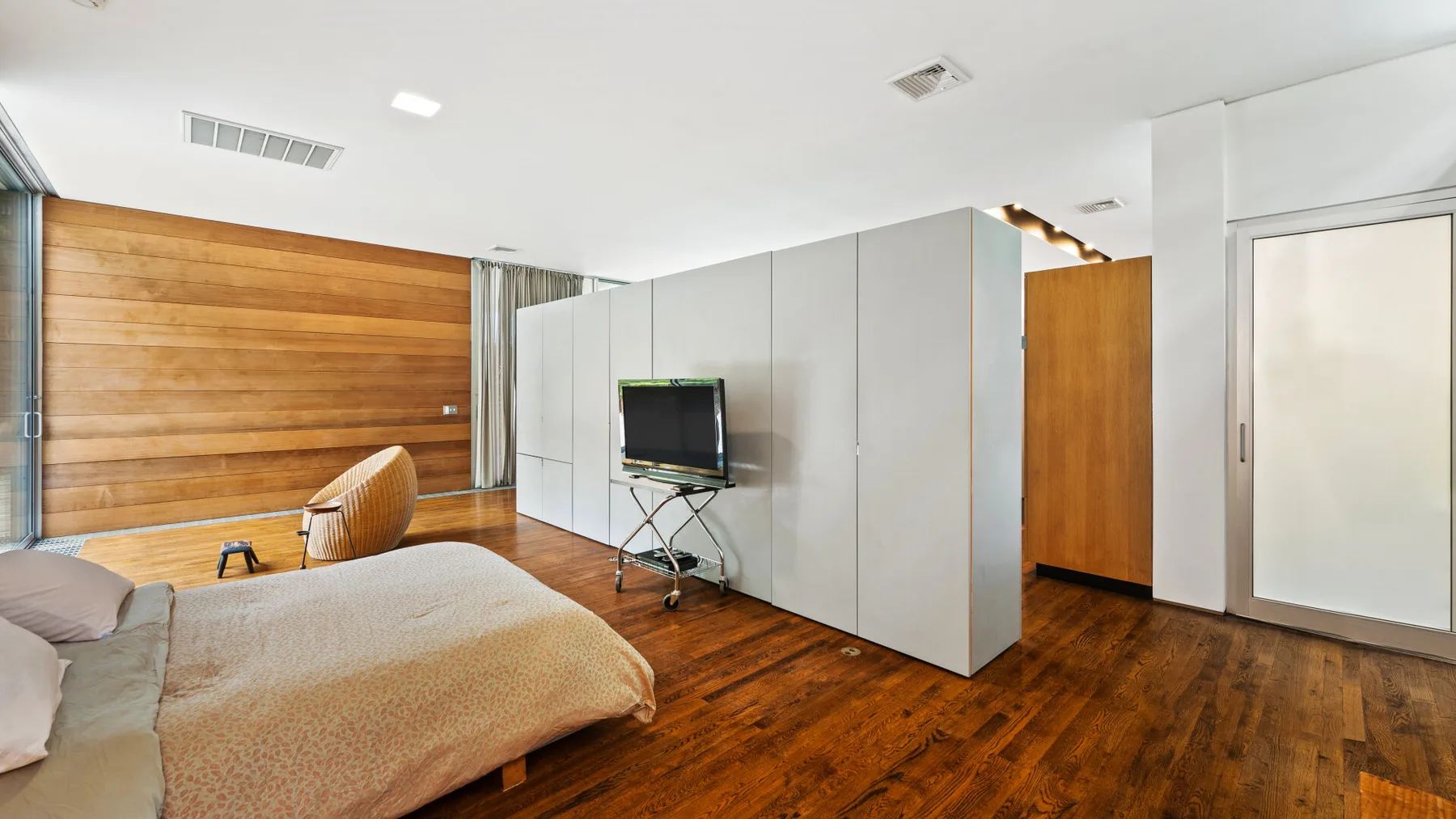 A bedroom with a bed, television, and wood-paneled wall.