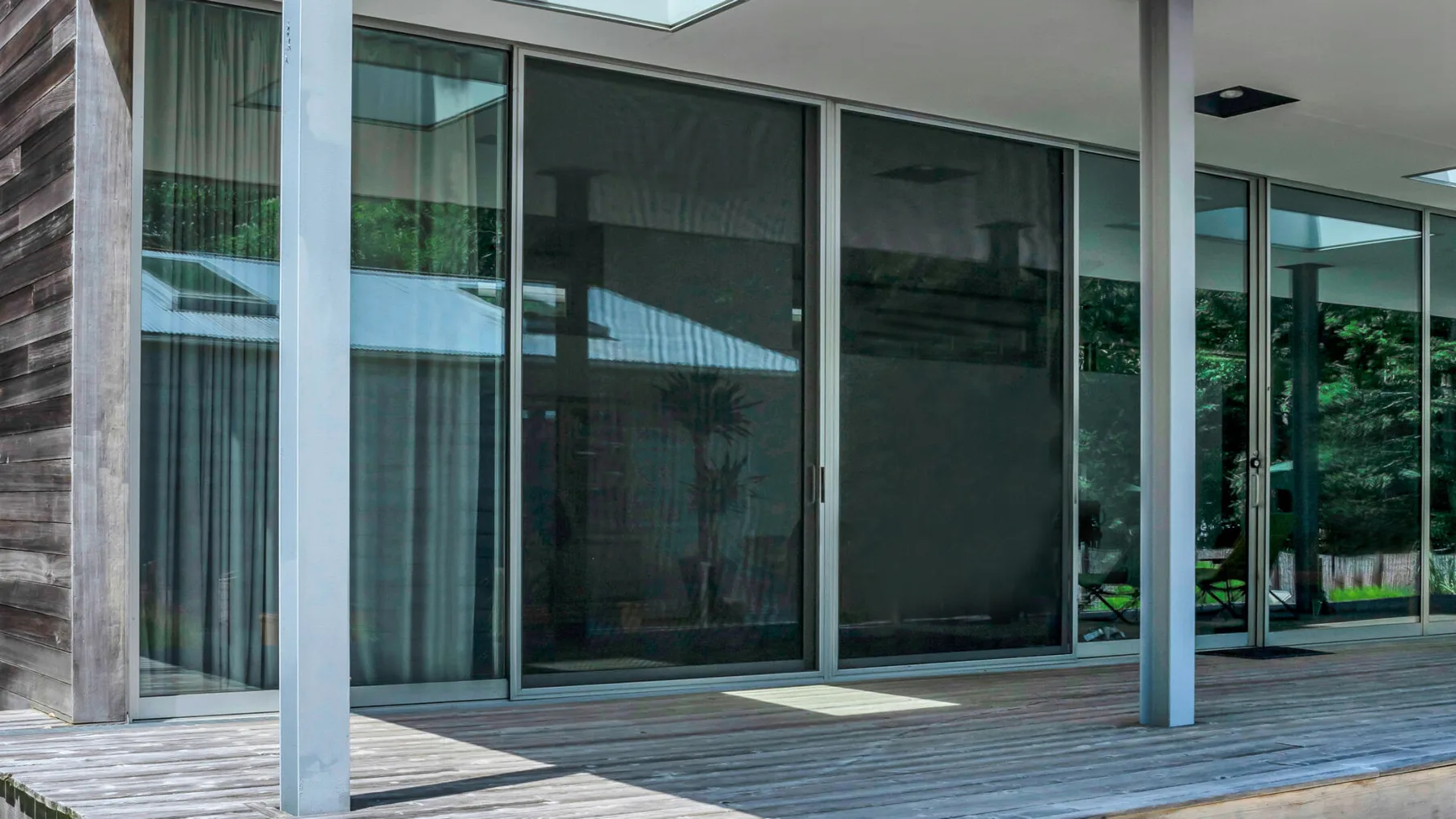 A covered patio with large glass doors opening onto a wooded view.