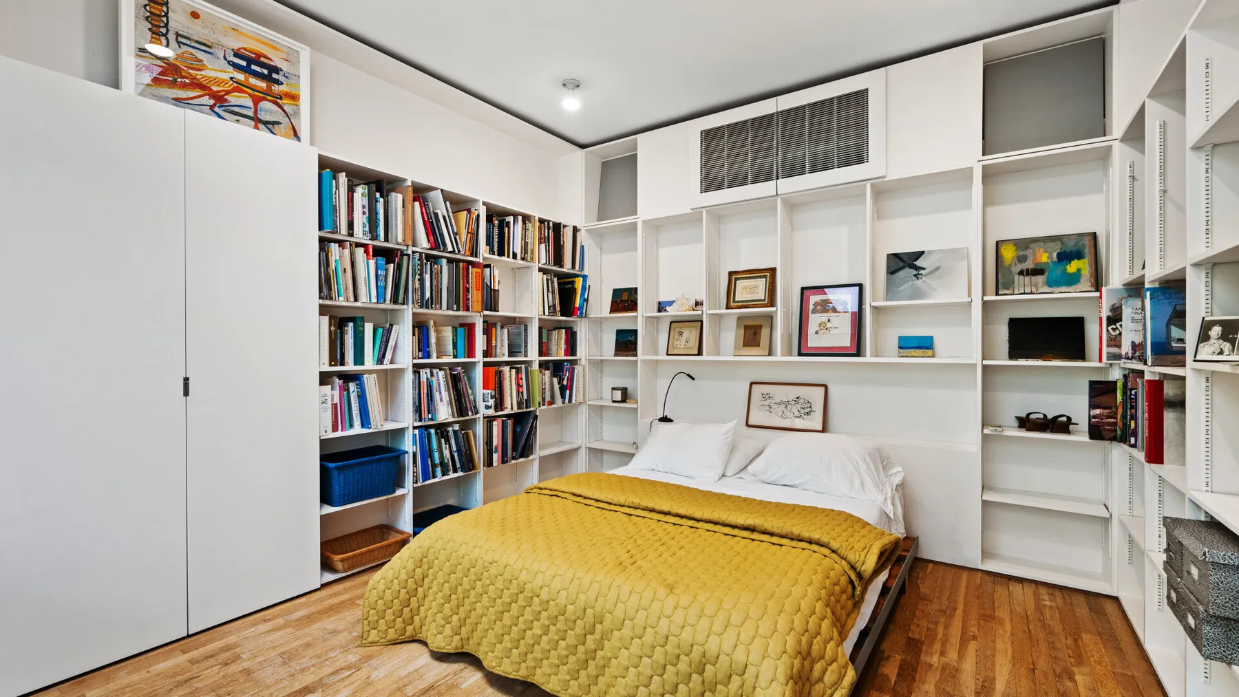 A bedroom with a bed and built-in bookshelves filled with books.